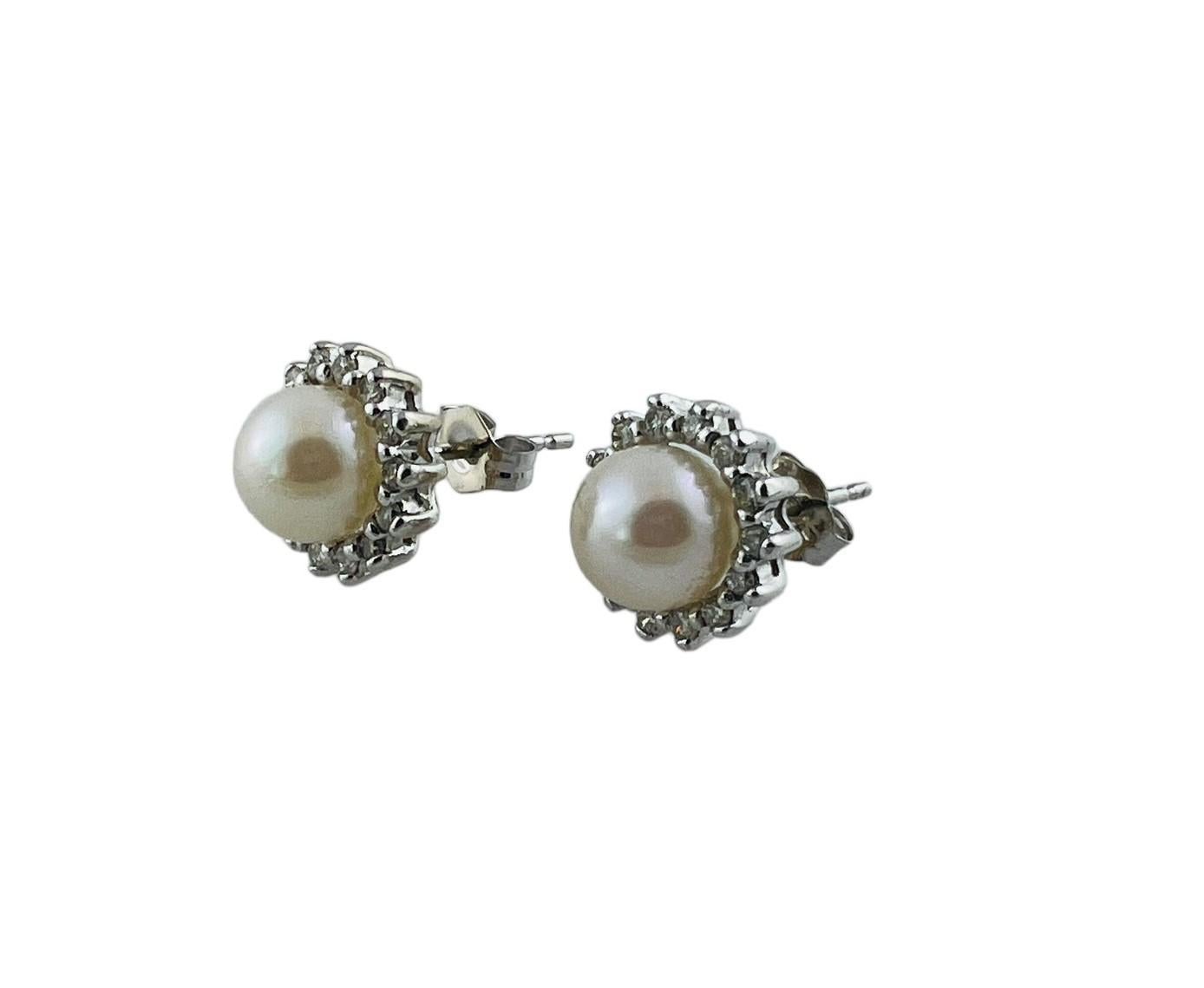 These lovely earrings each feature one white pearl (7 mm) and 14 round brilliant diamonds set in classic 14K white gold. Push back closures.

Approximate total diamond weight: .28 ct.

Diamond color:  I-J

Diamond clarity:  SI1-I1

Size:  10
