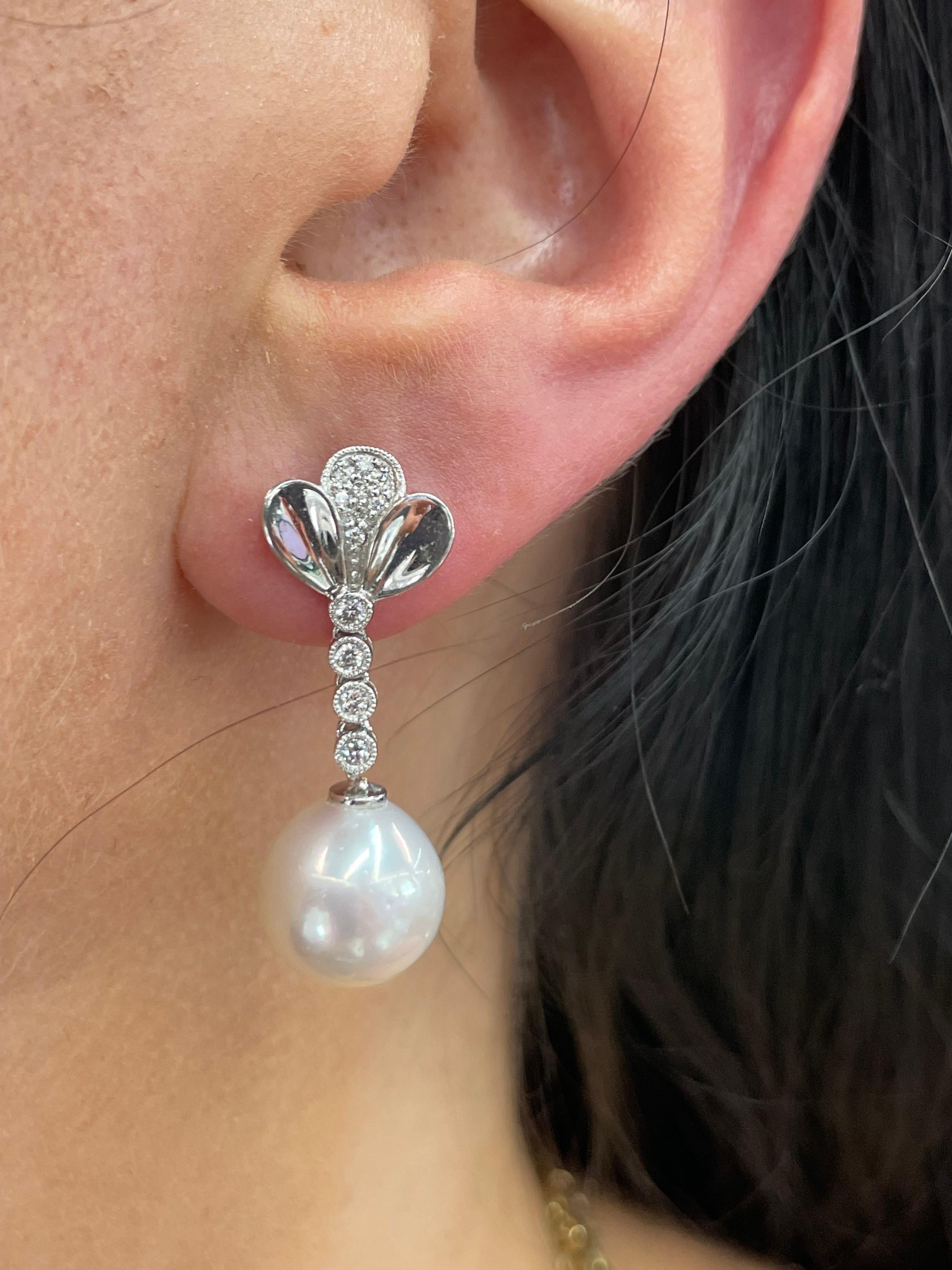 14 Karat White Gold floral motif drop earrings featuring 24 round brilliants weighing 0.24 carats and two South Sea Pearls measuring 11-12 MM.
Color G-H
Clarity SI

Comes in different gold & pearl colors.
DM for more information. 