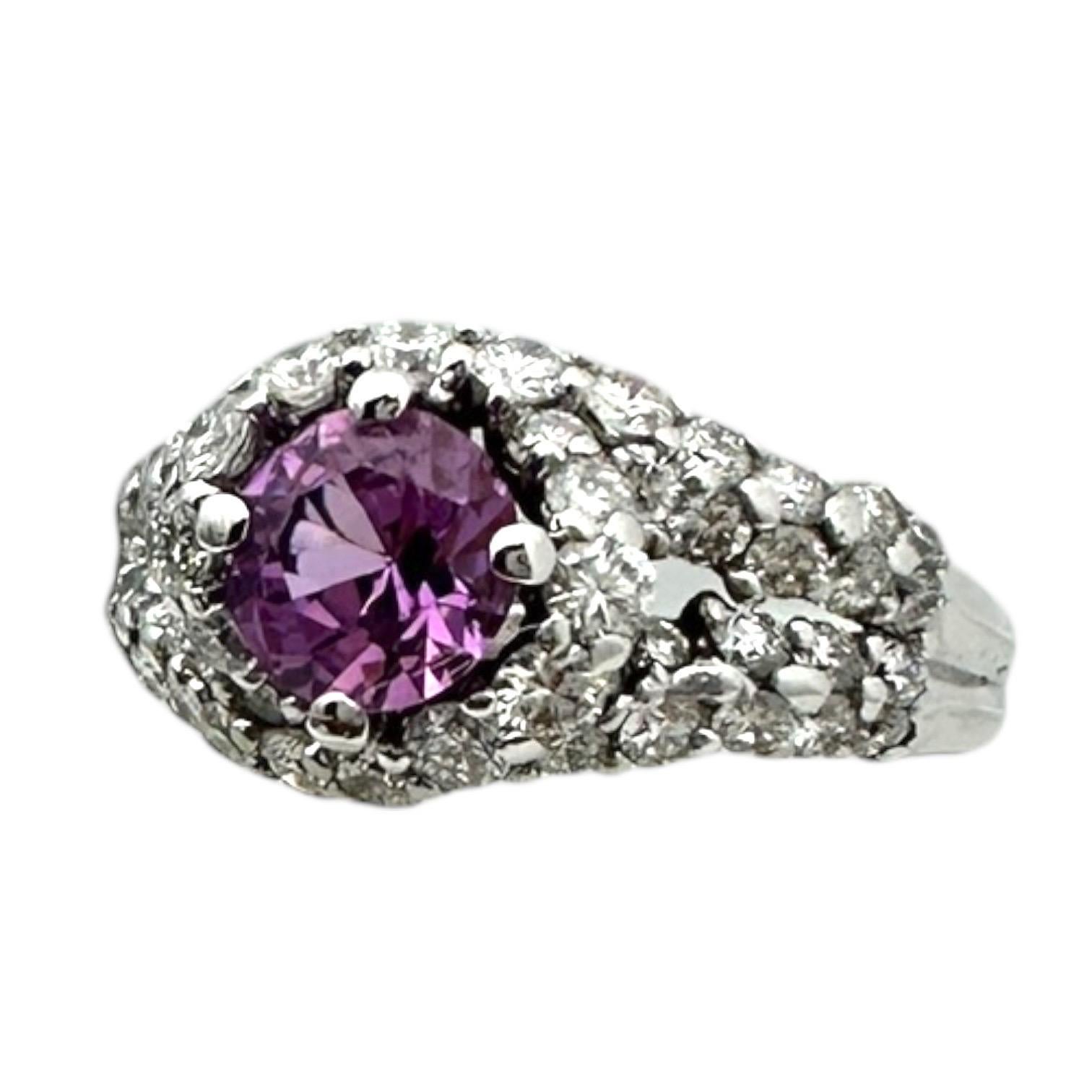 Dieser brandneue Ring besteht aus einem leuchtenden, natürlich rosafarbenen 6,11 mm großen Saphir mit einem Gewicht von 1,00 Karat, der von einem Halo aus Diamanten umgeben ist, die auf einer geteilten Schiene gefasst sind. Die Diamanten haben eine