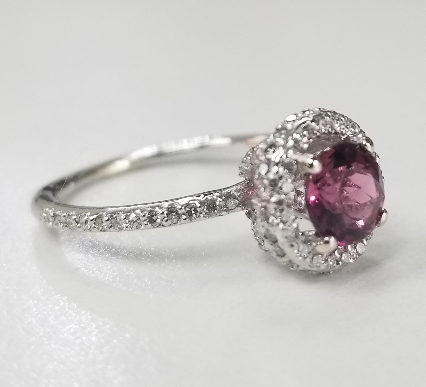 14 karat white gold Pink Tourmaline diamond halo ring, containing 1 round pink tourmaline of gem quality weighing .90pts.  Diamonds are set all over the setting.  This ring is a size 6.5 but we will size to fit for free.