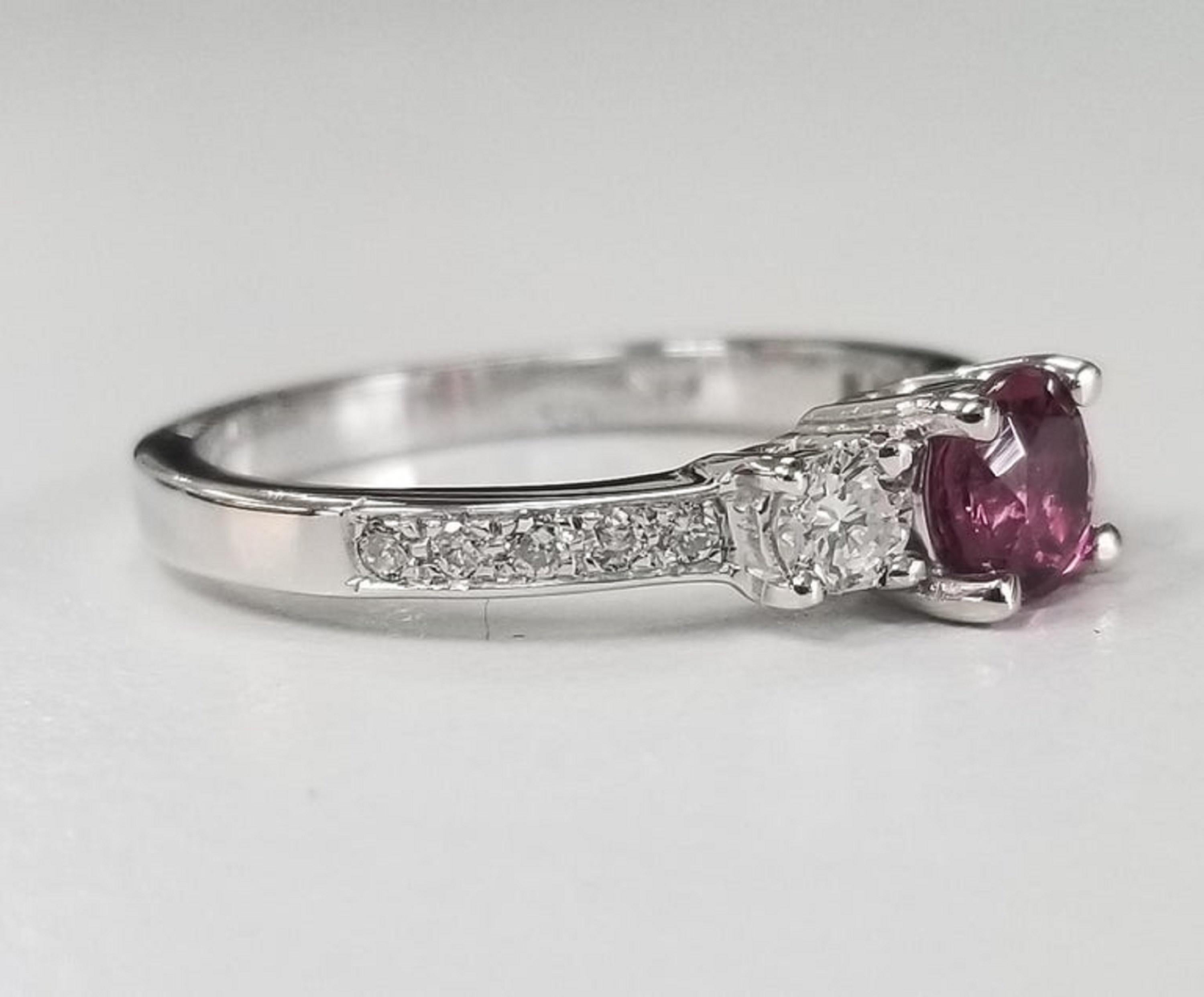 14 karat white gold Pink Tourmaline diamond ring, containing 1 round pink tourmaline of gem quality weighing .50pts., flanked with 2 round full cut diamonds on either side of fine quality weighing .24pts. and 10 round full cut diamonds of fine