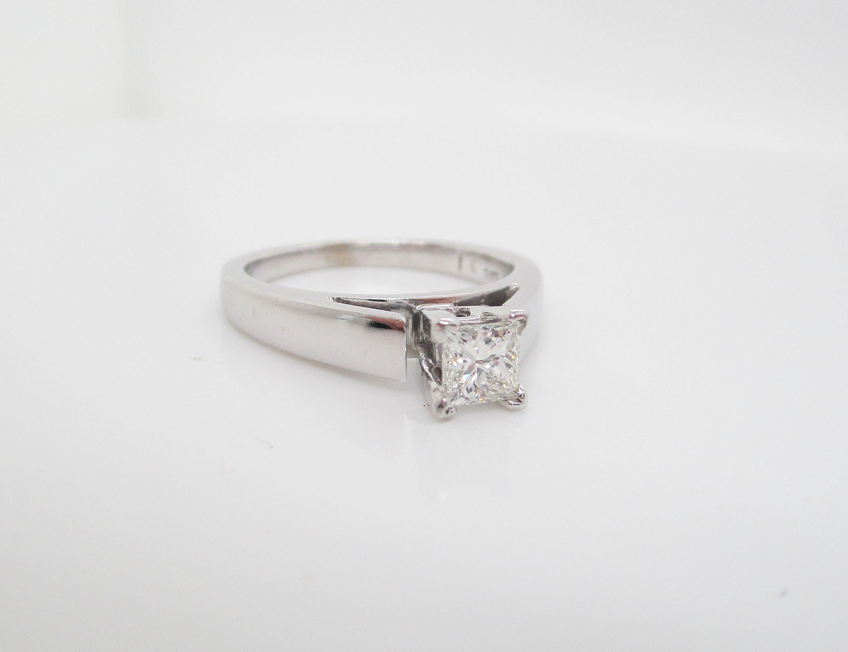 This is a gorgeous engagement ring in 14k white gold with a solitaire style princess cut diamond center! This is the epitome of a modern traditional engagement ring. The classic, sleek look holds the beautiful diamond front and center between four