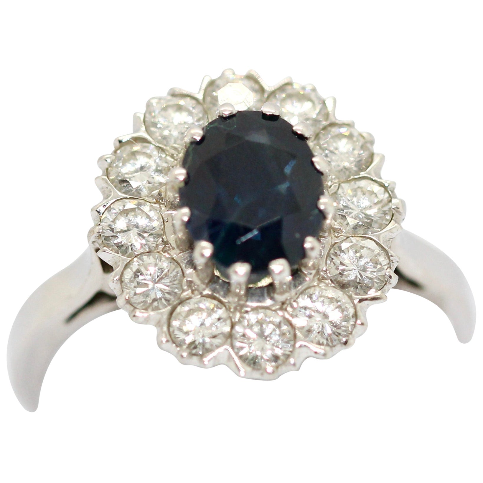 Anello in oro bianco 14 carati con uno zaffiro grande e 12 diamanti bianchi.