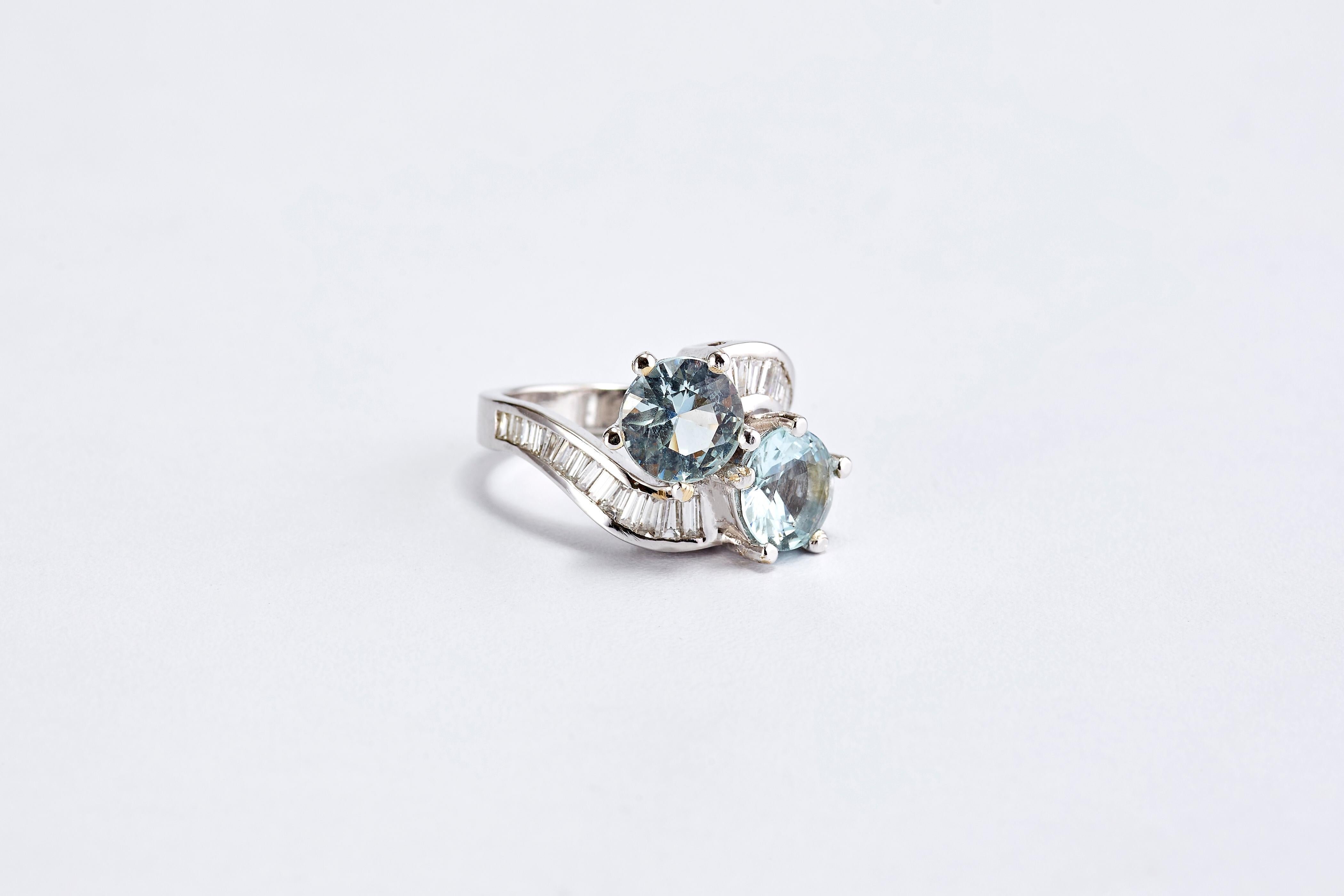 Anello in oro bianco 14 carati con 2 acquamarine e diamanti 
Due pietre centrali rotonde di acquamarina, seguite da due file di diamanti a baguette. Anello stupendo e di grande effetto, molto in stile.
L'acquamarina ha un peso totale di 5,5 carati.