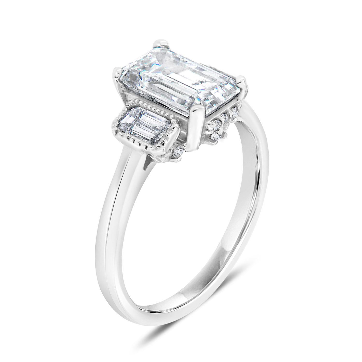 Cette élégante bague présente un diamant naturel de 1,63 carat de couleur G et de pureté I1, certifié par le GIA 5202275951, flanqué de deux diamants naturels parfaitement assortis de forme émeraude d'un poids de 0,39 carat. Douze petits diamants
