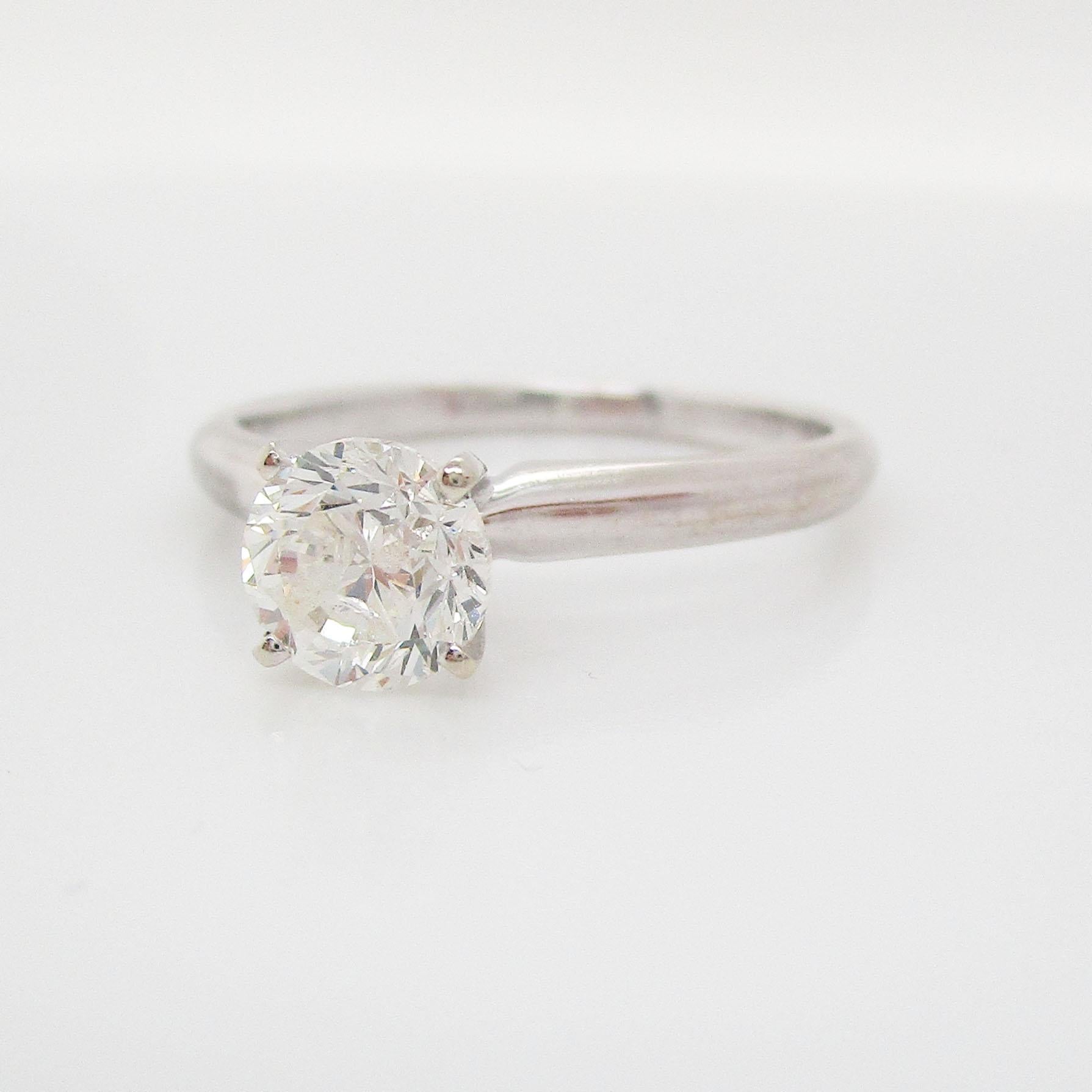 This is a beautiful diamond engagement ring in 14k white gold with a classic solitaire style. The four-prong setting is slightly raised, lifting the gorgeous round diamond. The white gold paired with the round diamond makes for a timeless, classic