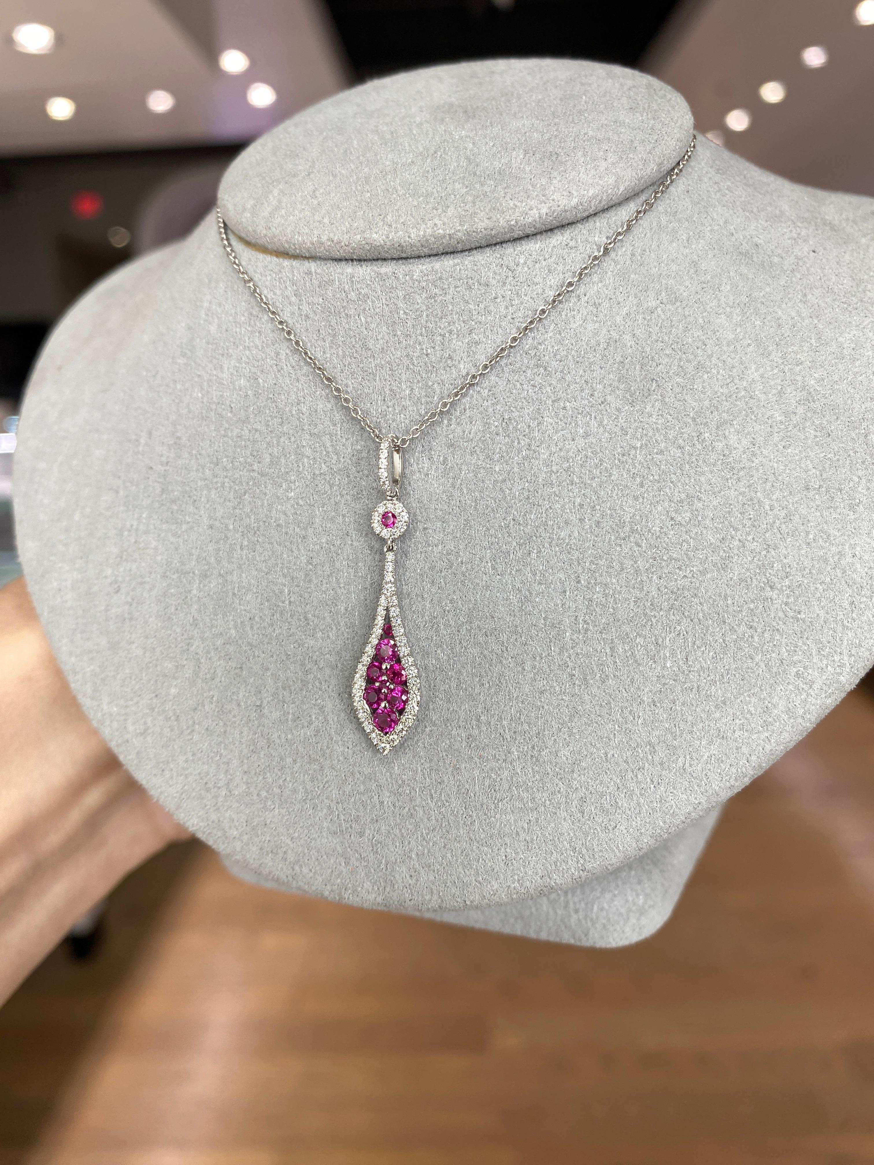 Ce pendentif exquis, réalisé en or blanc poli 14 carats, met en valeur des rubis ronds d'un poids total de 0,40 carat, accentués par des diamants ronds d'un poids total de 0,50 carat. Il est monté sur une chaîne en câble de 1 mm d'une longueur de
