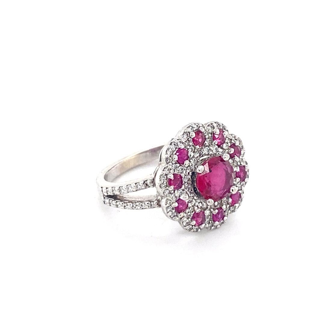 This 14 karat white gold ring has a round ruby center and features a floral style halo. Custom made by our expert jewelers this ring has 1.61cttw of rubies and 0.60cttw of diamonds. The ring is a size 6 and has a diamond split shank band. 