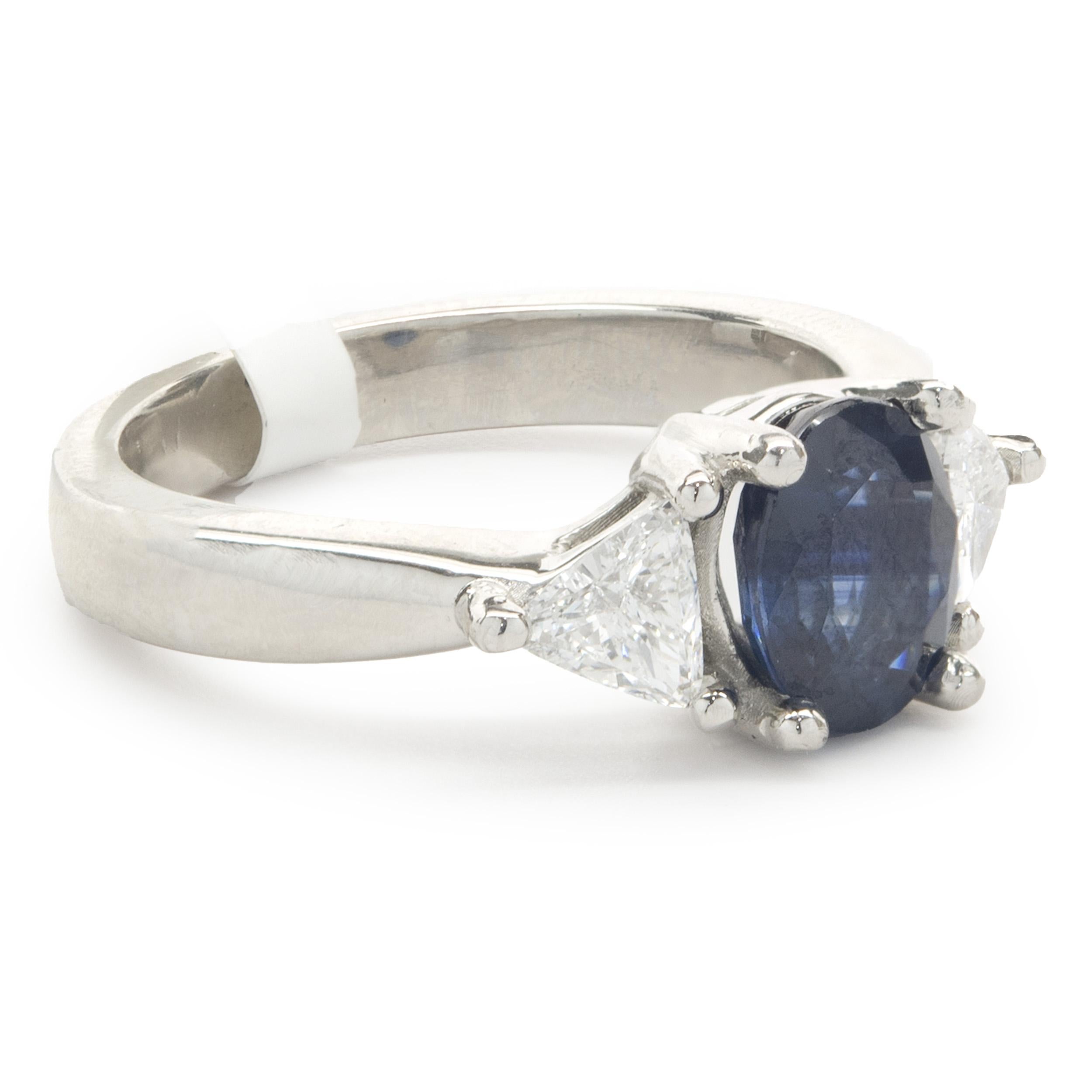 Designer: custom
Material: 14K white gold
Diamond: 2 trillion cut = 0.81cttw
Color: G
Clarity: SI1
Sapphire: 1 oval cut =- 1.89ct
Dimensions: ring top measures 8mm wide
Ring Size: 6.5 (complimentary sizing available)
Weight: 9.02 grams