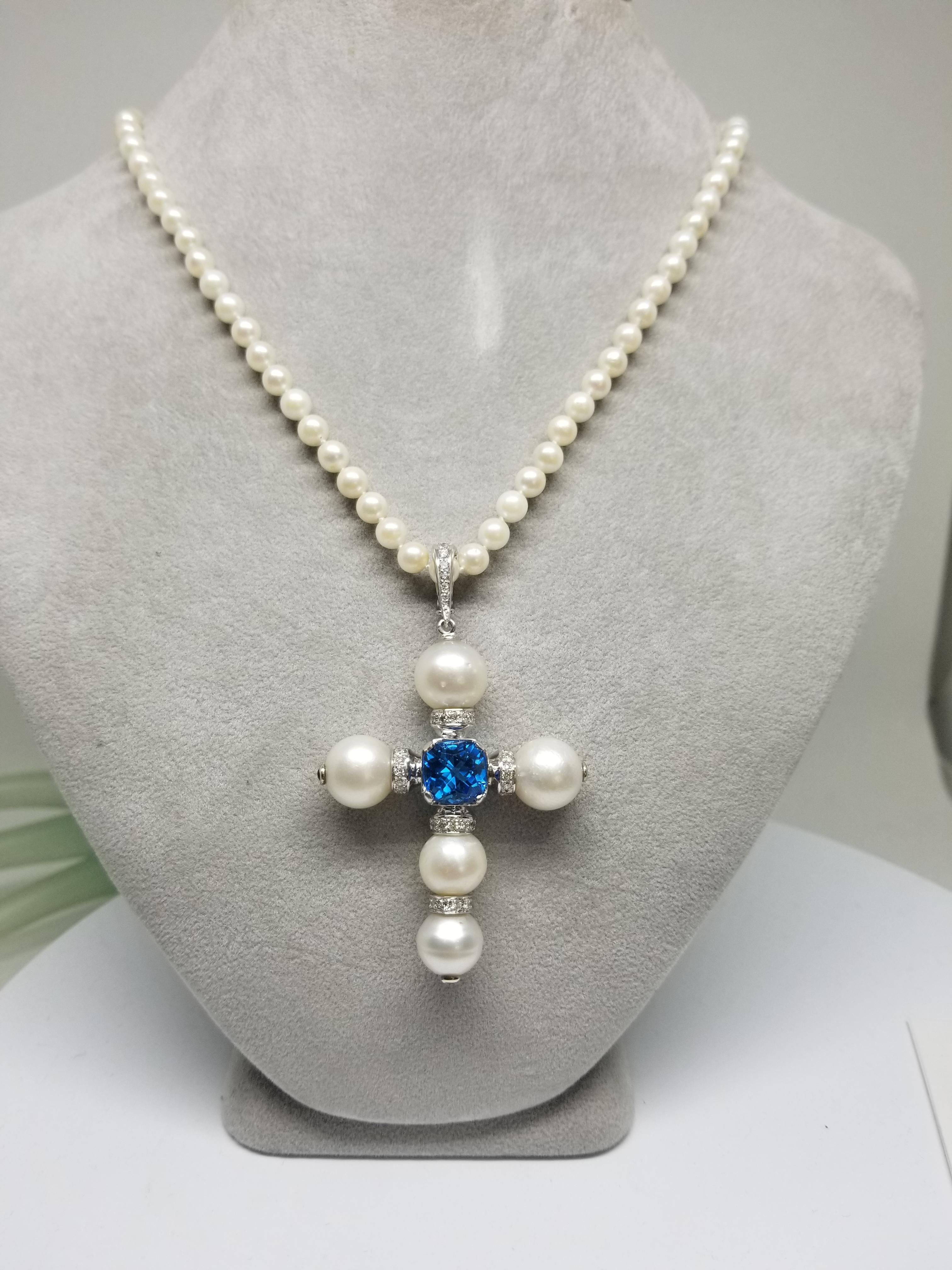 14k white gold South Sea Pearl cross with 5 pearls measuring 10.5-12mm, with a cushion cut swiss blue topaz weighing 5.03cts., 25 round full cut diamonds weighing .53pts. and 3 round sapphires as accents on the ends of the pearls set in a bezel. 