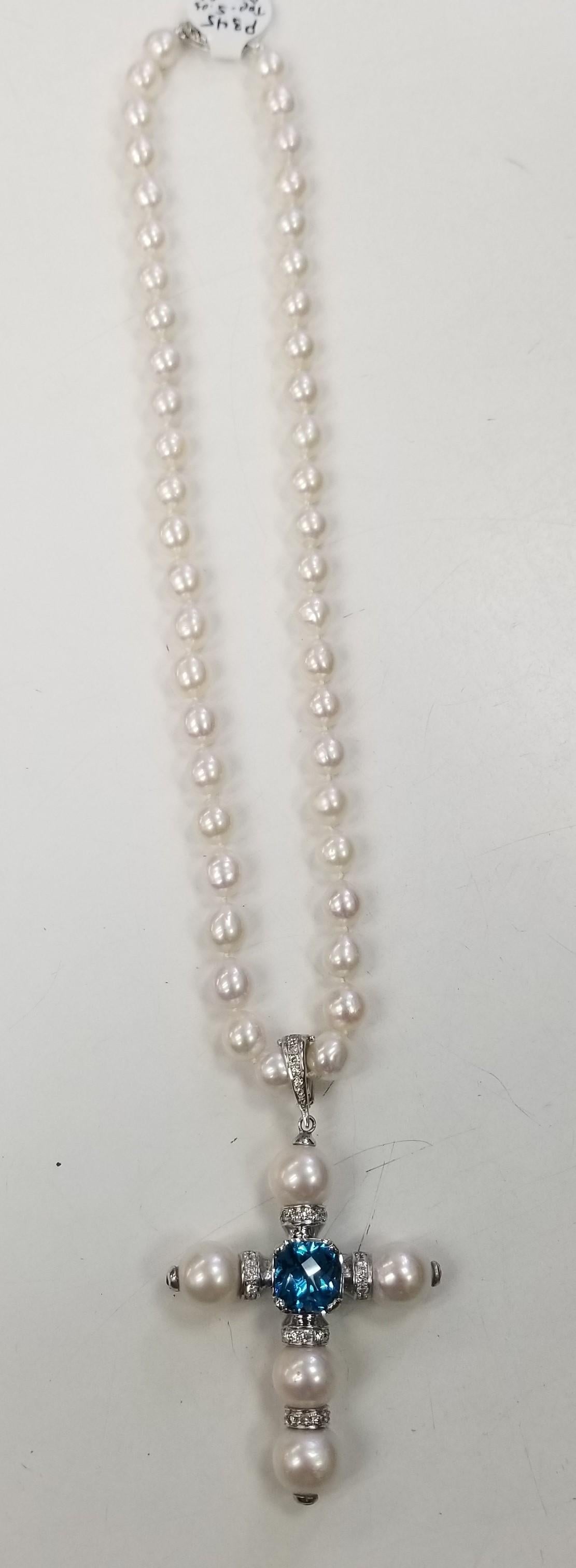 14k white gold South Sea Pearl cross with 5 pearls measuring 10.5-12mm, with a cushion cut swiss blue topaz weighing 5.03cts., 25 round full cut diamonds weighing .53pts. and 3 round sapphires as accents on the ends of the pearls set in a bezel. 