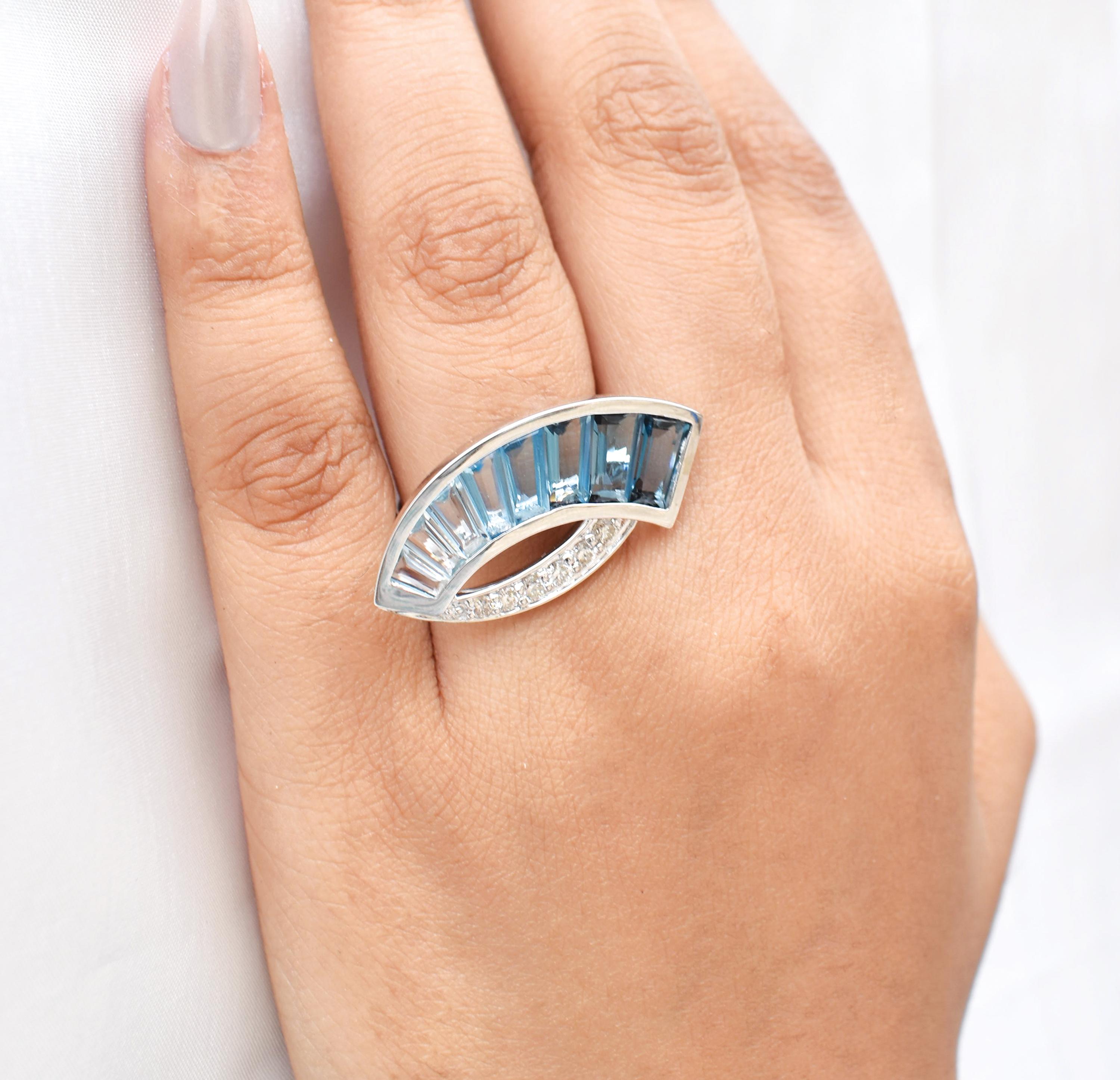Sculptural and sophisticated, this 14K White Gold Diamond Ring is a striking expression of contemporary elegance and fine craftsmanship. Its gracefully curved silhouette showcases a stunning arrangement of tapered baguette-cut blue topaz gemstones,
