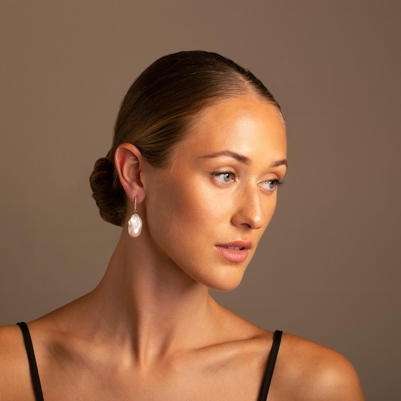 14K Vertical Gold Bar with a beautiful soft shade of orange sapphire and baroque pearl drop earring.
The hue of orange sapphire against the high polish white gold contrasts beautifully with the pearl, and the shimmering vertical bar gives the