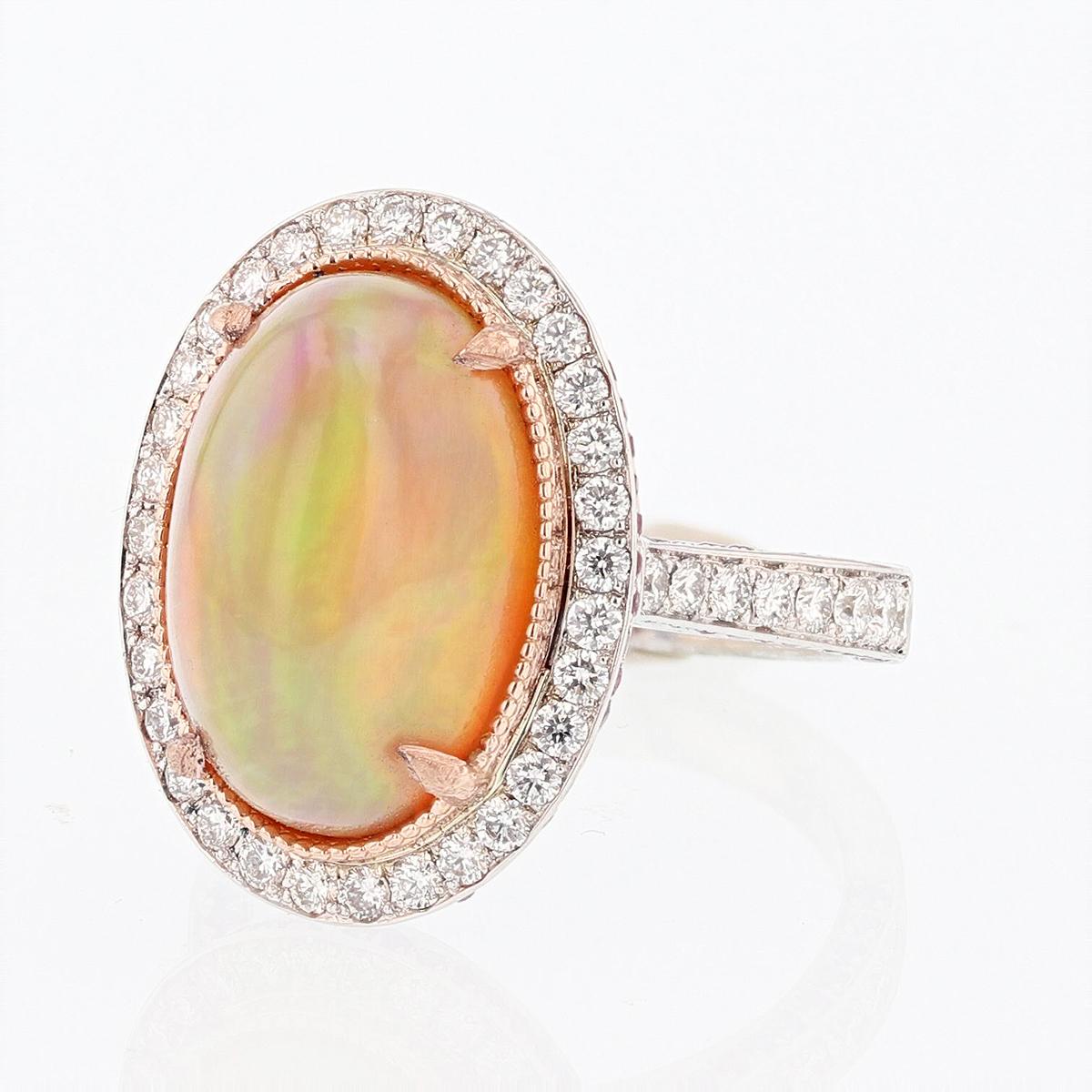 This ring is made with 14 karat white and rose gold and features an 5.89ct oval cut Opal and is surrounded by 100 pavé set round cut pink sapphires weighing 0.46ct and 48 round cut diamonds weighing 0.78ct with a color grade of (G) and a clarity of