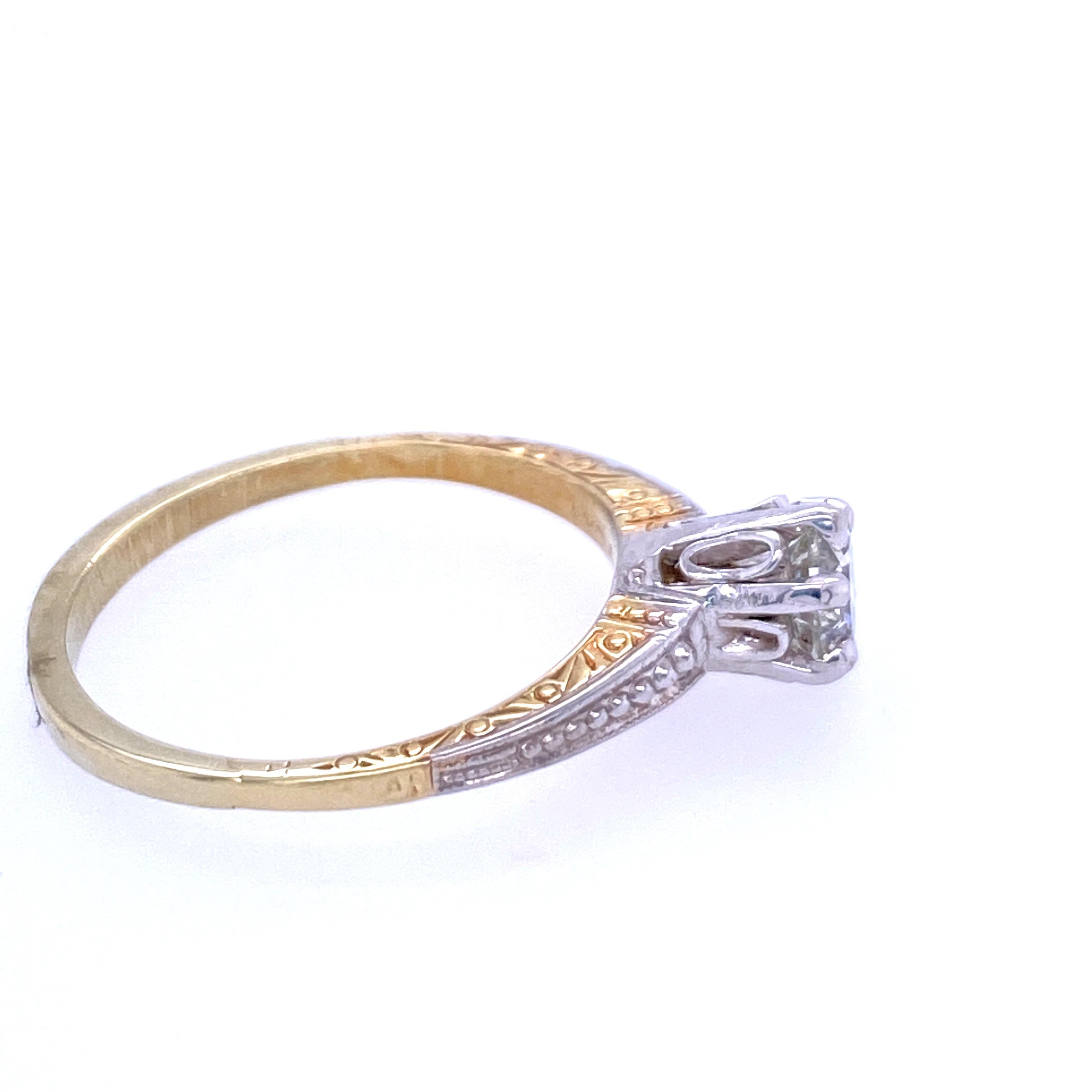 One 14 karat yellow and white gold (stamped 14K) engagement ring prong set with with one 0.57 carat round brilliant diamond with K color and I1 clarity.  The diamond is set in a six prong white gold engraved mounting with a beaded white gold top. 