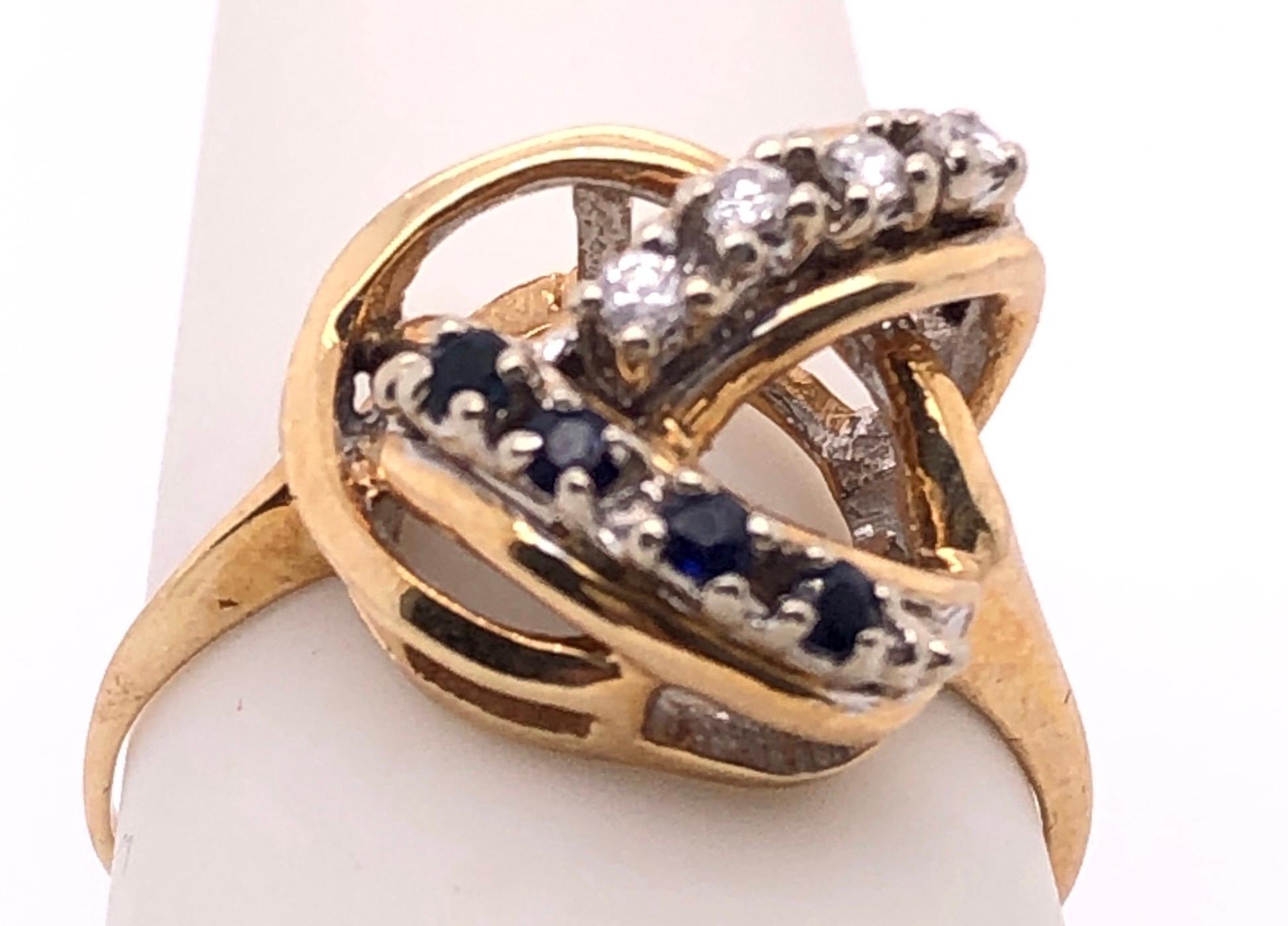 14 Karat Yellow Gold Contemporary Ring with Sapphires and Diamonds The prongs are in white gold. 
0.12 TDW.
Size 6.5
3 grams total weight.