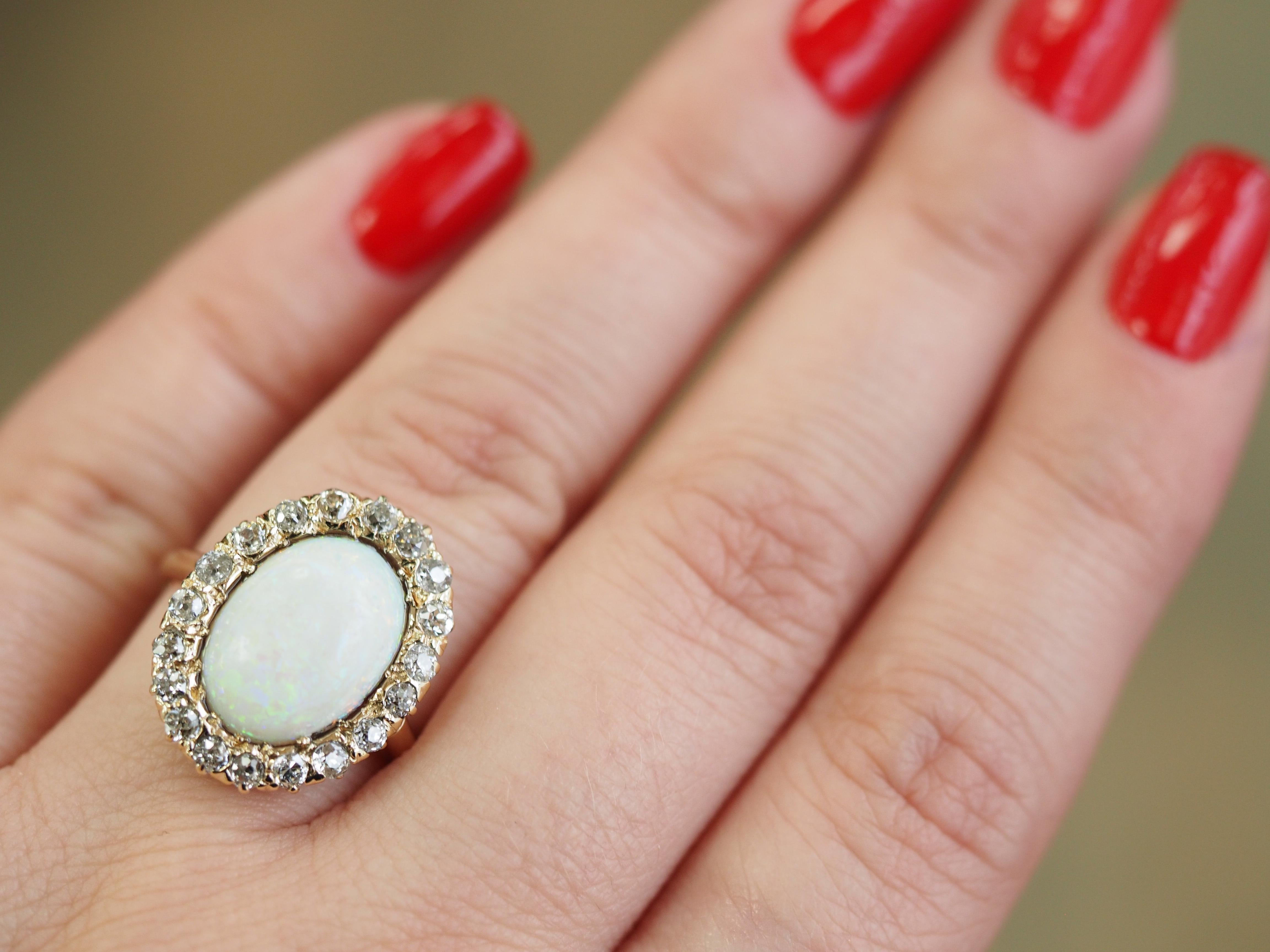  Estate 14K Gelb- und Weißgold Opal und Diamant Cocktail Ring.  Der Ring zeigt einen schönen ovalen Opal, der von einem wellenförmigen Halo aus Diamanten im Rundschliff umgeben ist.  Der Stein ist in eine vierzackige Fassung aus 14-karätigem