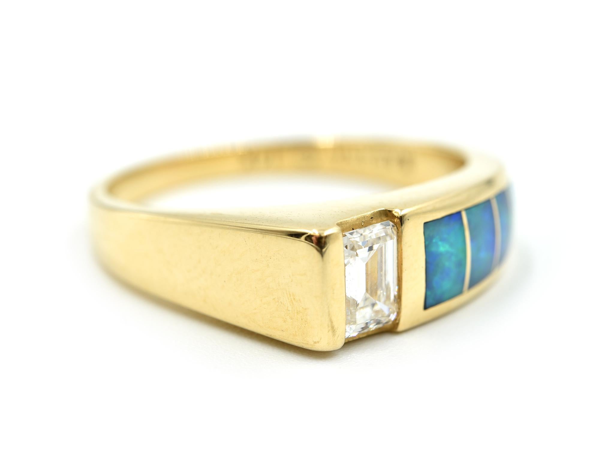 This is a 14k yellow gold band made with a 0.50ct emerald cut diamond and features opal inlays on top! The diamond is graded G in color and VS2 in clarity. Each of the opals graduate in size on the band. The top of the band measures 21mm in length
