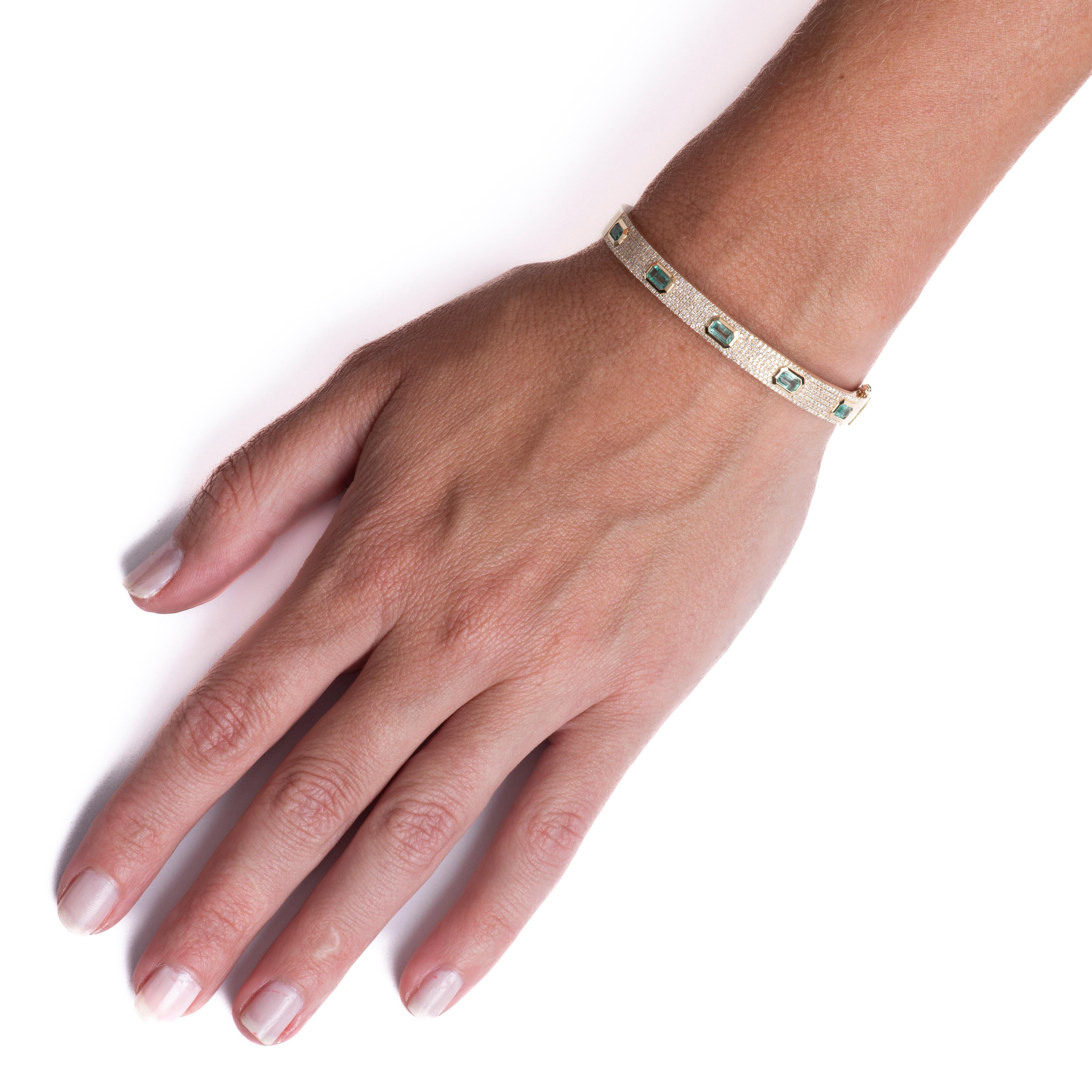 This bangle features five emerald cut emeralds with a total carat weight of 1.47 carats accented by 0.74 carat total weight in round diamonds set in 14 karat yellow gold. Box with safety clasp. Wear alone or layer with your other favorite bracelets.