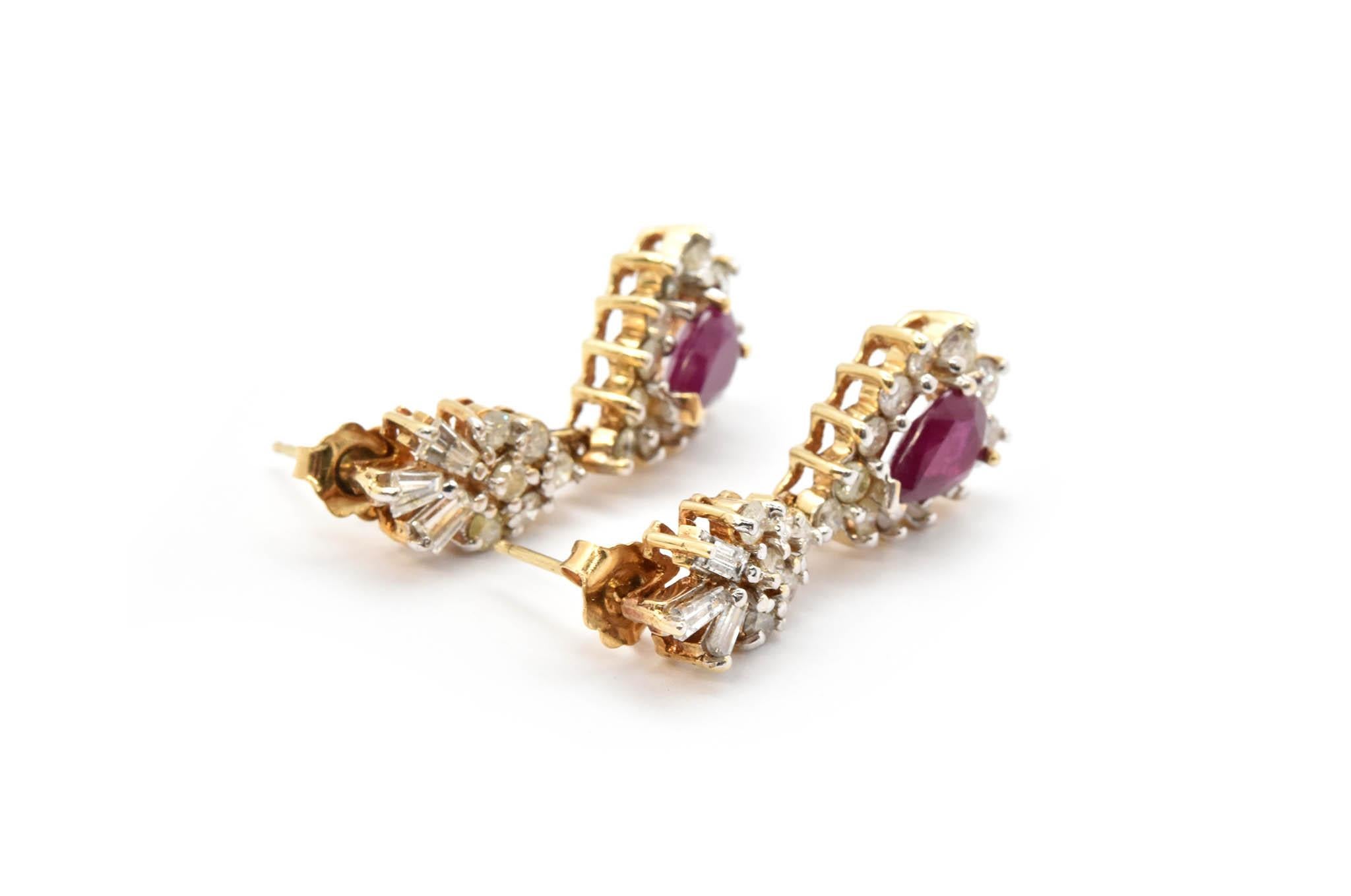 These drop earrings are crafted in 14k yellow gold. Each earring holds a pear cut ruby weighing 1.25cts, for a total weight of 2.50cts. In addition, each earring holds round cut and baguette diamonds. The round brilliant cut diamonds have a total