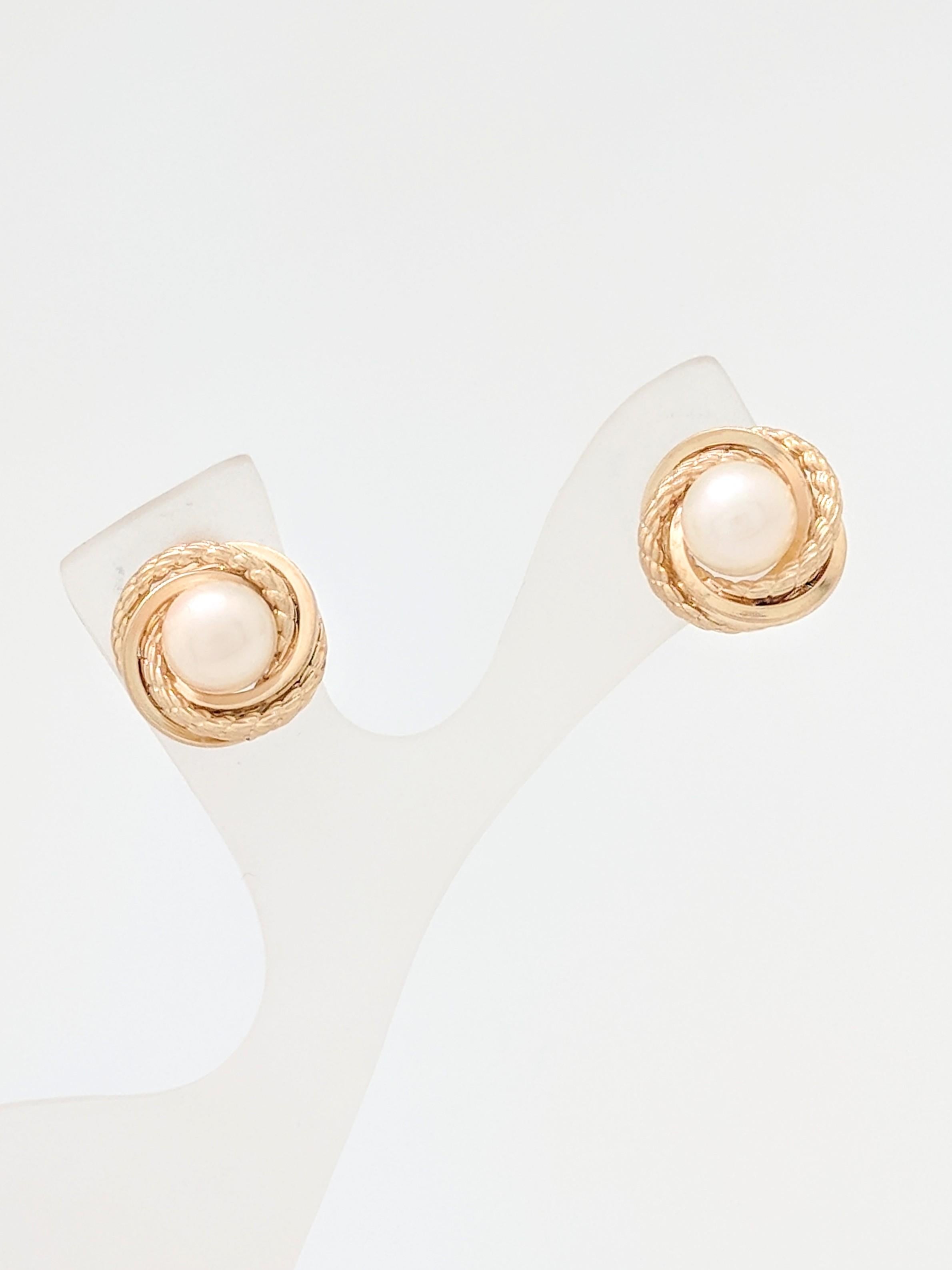 You are viewing a pair of Freshwater Pearl Stud Earrings. These earrings are crafted from 14k yellow gold and weigh 2.6 grams. Each earring features (1) 6mm freshwater pearl inset in a gold swirl design. The earrings measure 12mm in diameter and