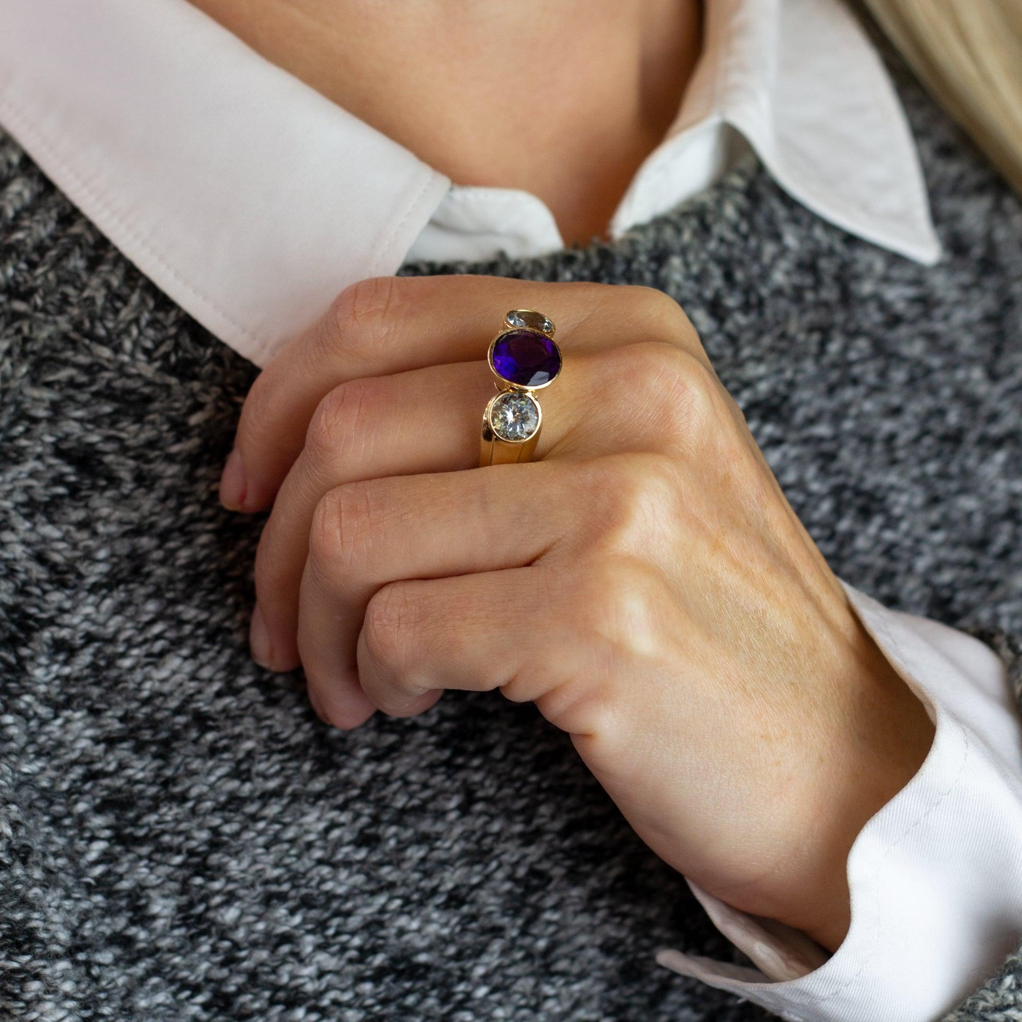 A bold 14 karat yellow gold dress ring set with a pair of aquamarines and a single amethyst. The three stone ring features tapered grooved shoulders and centres on a single round amethyst weighing 3.0 carat, flanked by a pair of round aquamarines