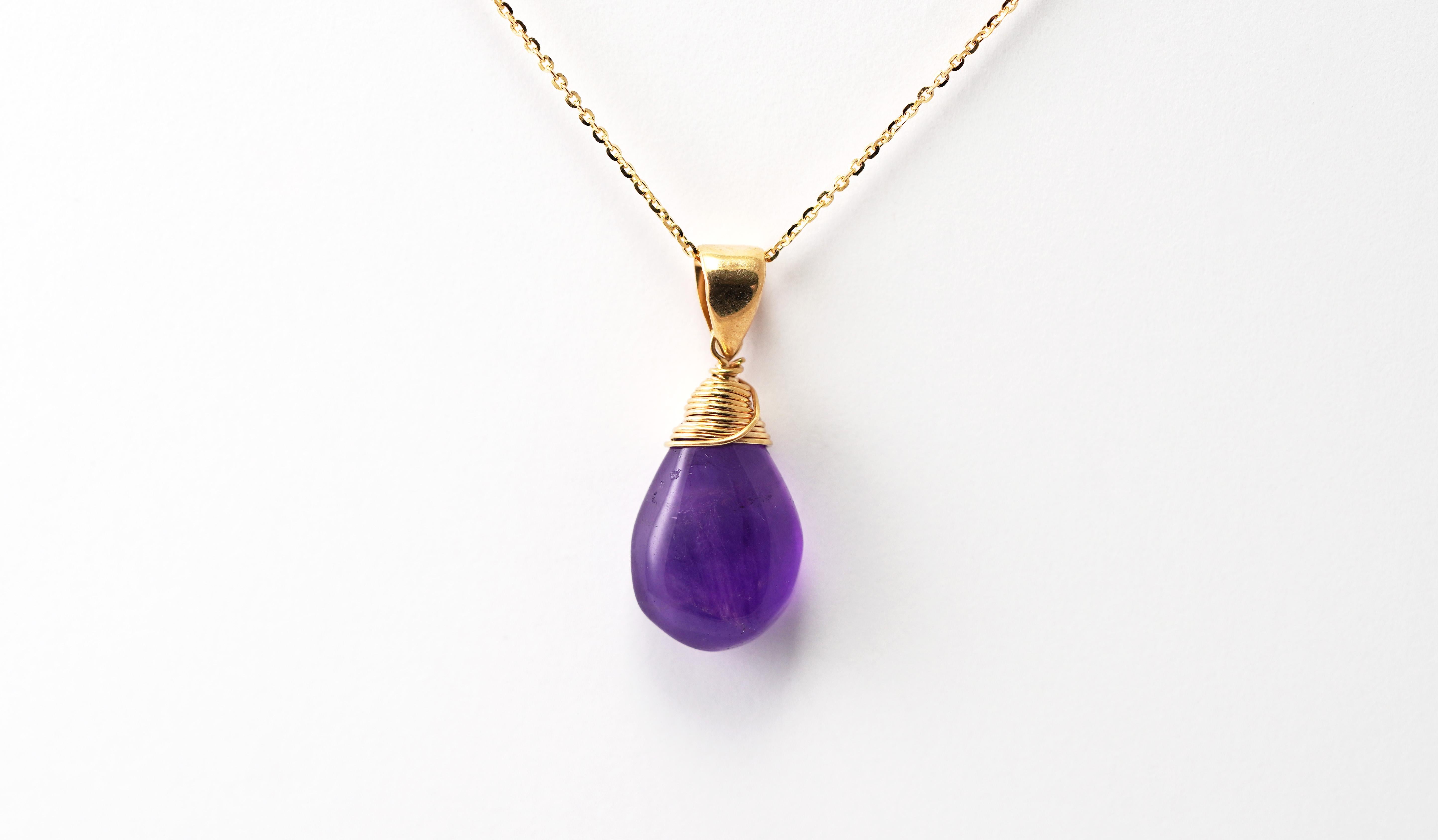 Célébration de l'élégance et de la beauté naturelle, ce collier artisanal d'Antonio Gems est orné d'une lumineuse améthyste taillée en cabochon et enveloppée d'or jaune 14 carats. La teinte violette profonde de la pierre précieuse s'illumine