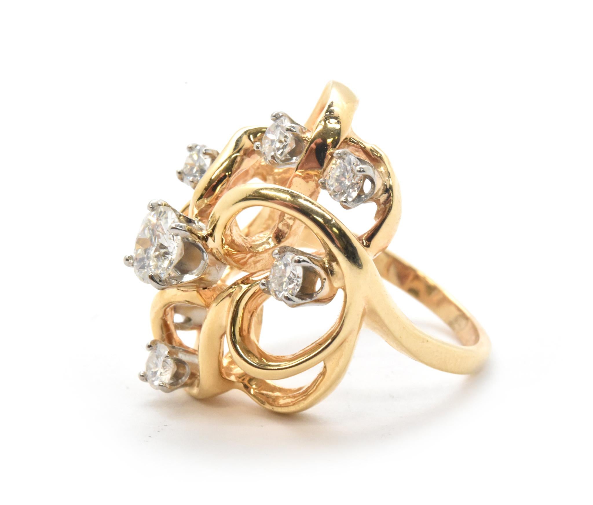 This beautiful ring is designed in 14k yellow gold, and it holds 7 round brilliant-cut diamonds for a total weight of 1.10 carats. The diamonds are graded I-J in color and SI in clarity. This cocktail ring measures 23mm wide, and it weighs 8.85