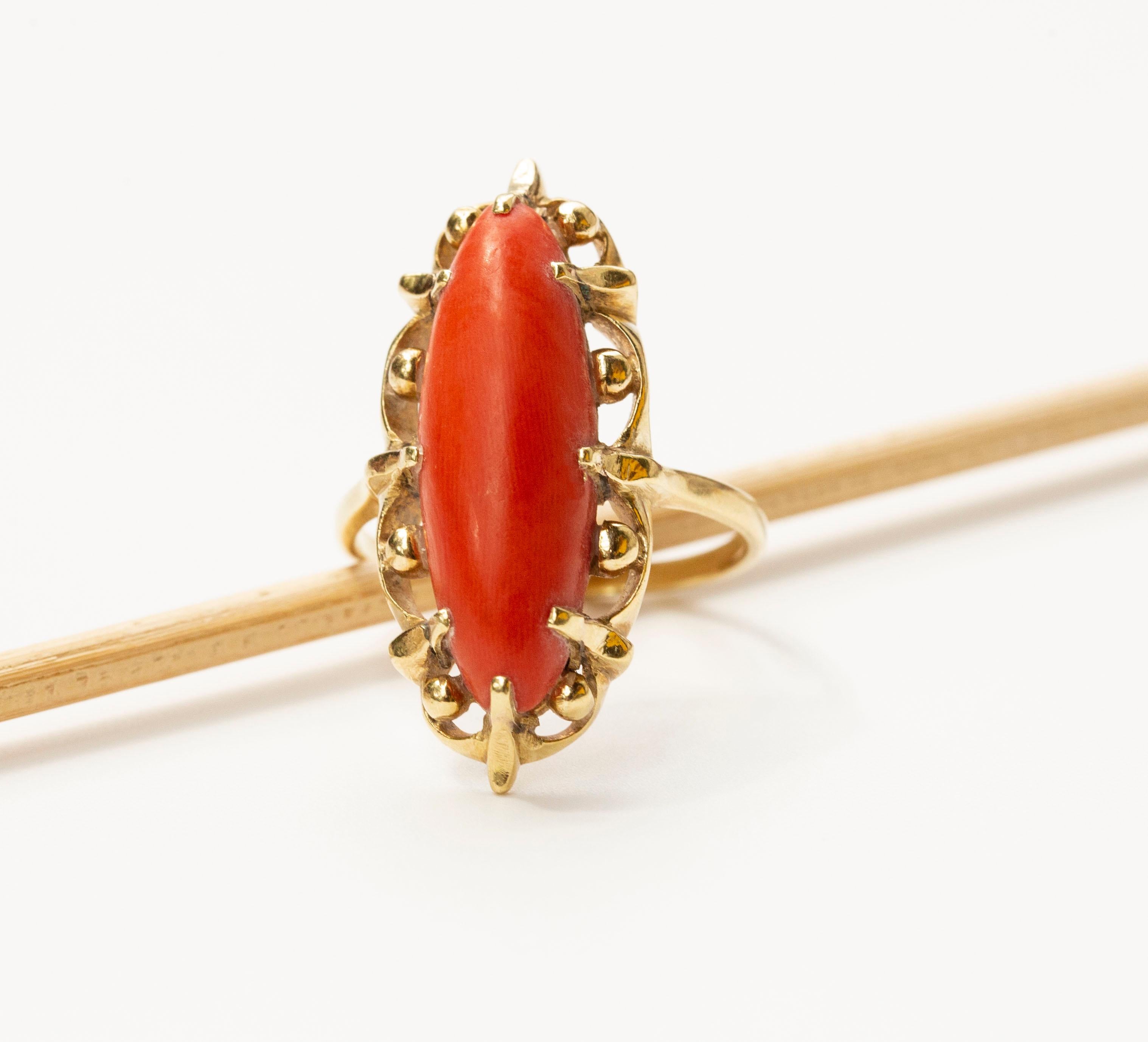 A vintage (ca. 1970 s) 14 karat solid yellow gold with natural red coral cabochon. The red coral is set in an oval gold frame with scalloped edge and gold spheres. The ring is marked with an oak leaf that is the Dutch mark for the 14 karat gold. In