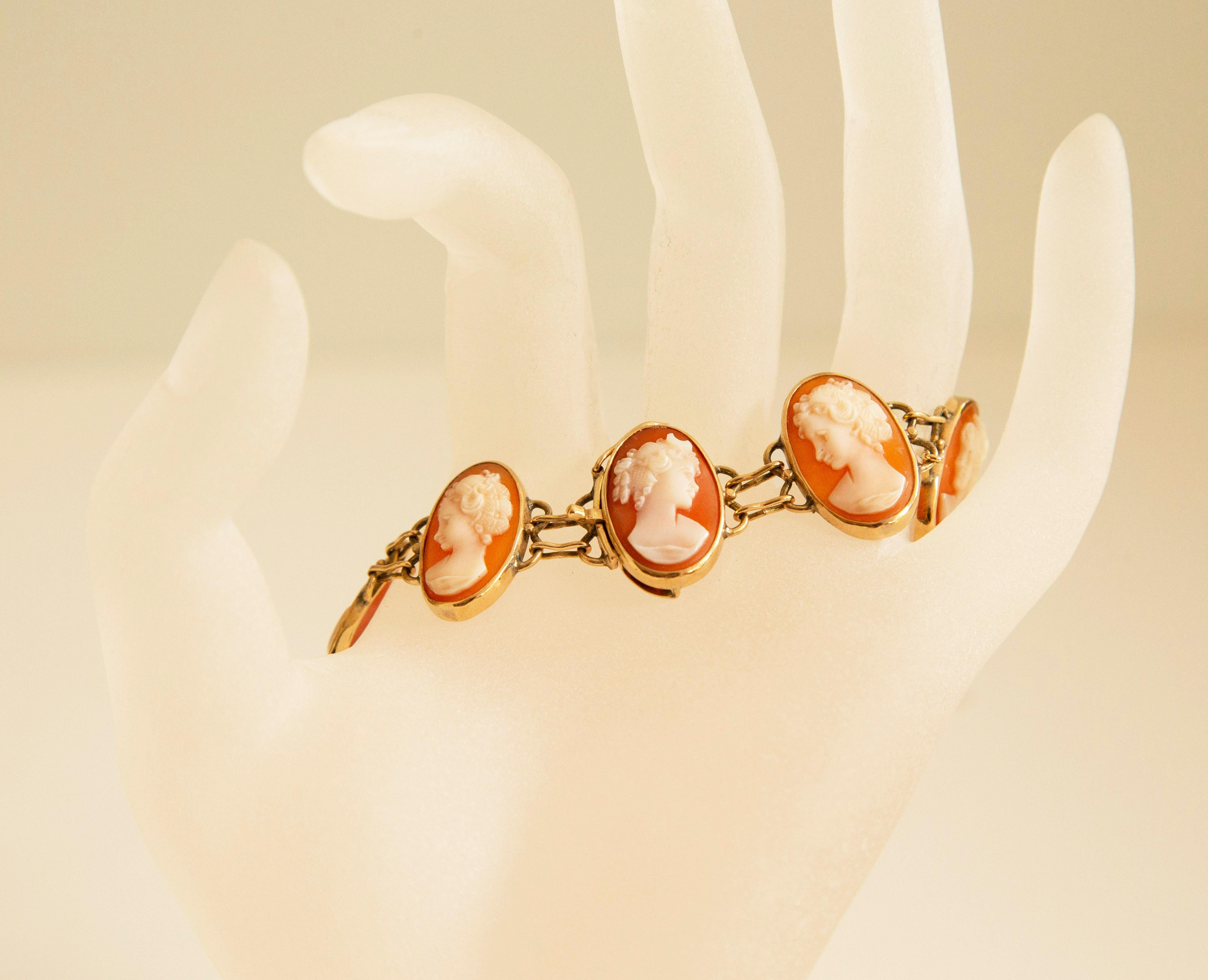 A vintage 14 karat (krt) yellow gold and hand carved shell cameo link bracelet. The bracelet features nine cameos in oval 14 krt setting. Each cameo features an unique female silhouette in the Victorian style. The bracelet closure is stamped with