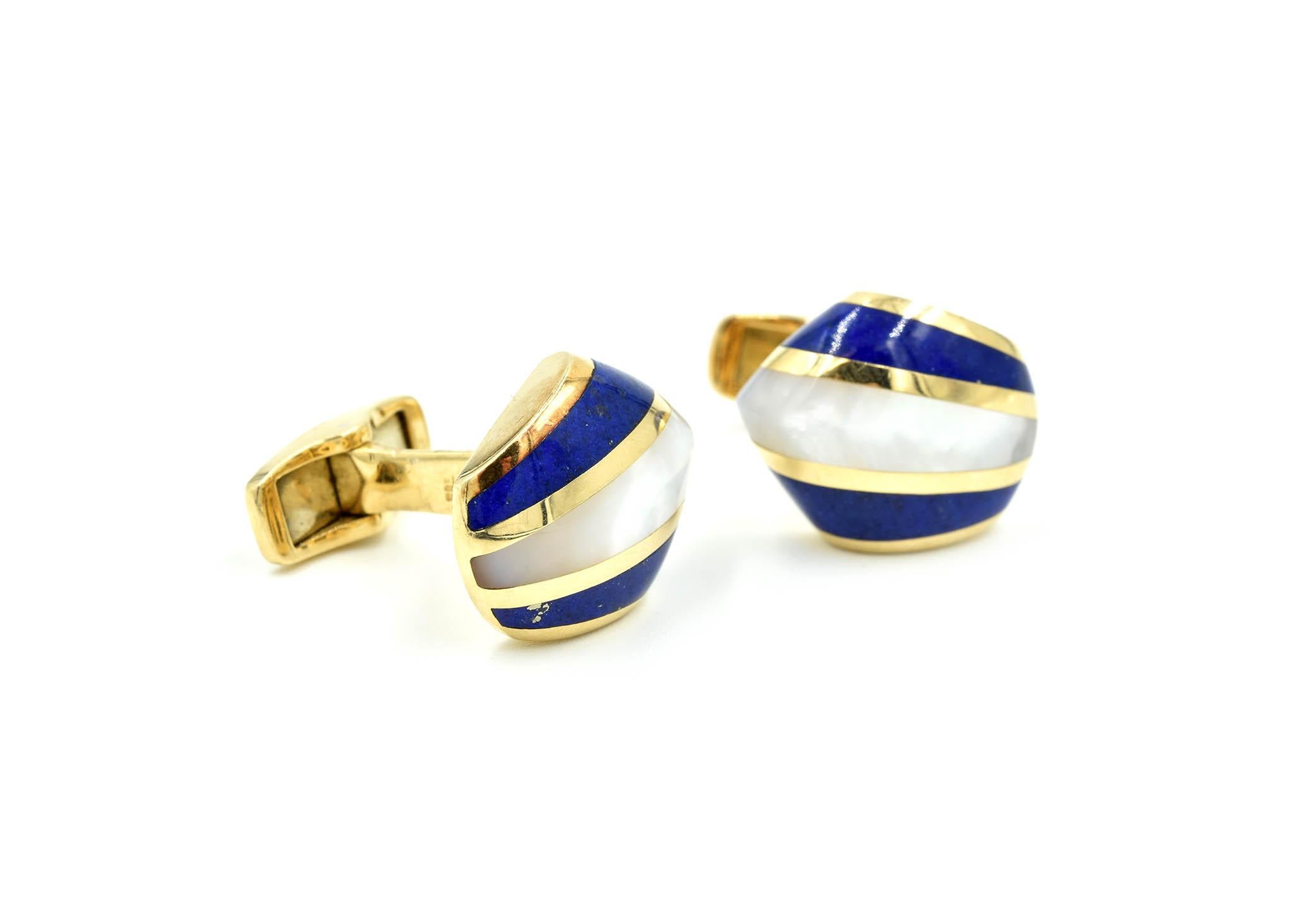 This pair of button style cufflinks is styled in 14K yellow gold. The cufflinks feature a center inlay of white mother-of-pearl flanked by stunning blue lapis lazuli. Each section is framed by high-polished yellow gold. The cufflinks measure 19x15mm