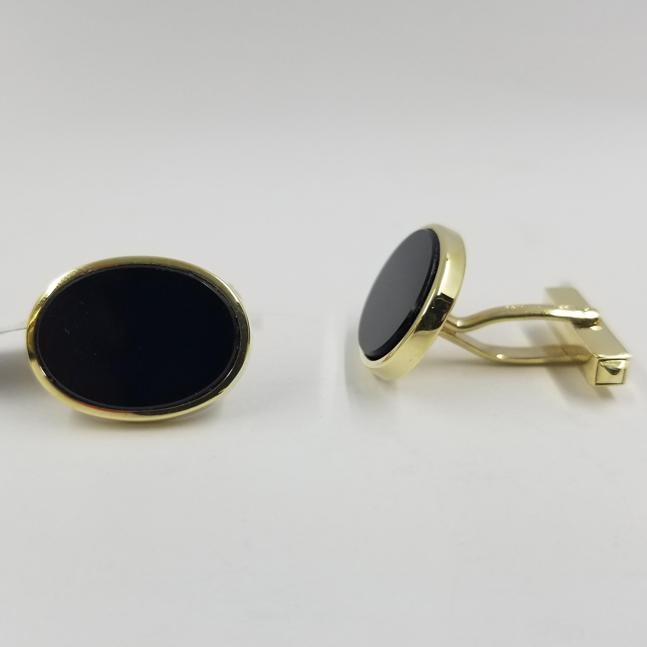 Set of 2 cufflinks crafted in 14 karat yellow gold (stamped). The front is a polished bezel surrounding oval cut flat onyx. The backs are hinged for easy dressing.
