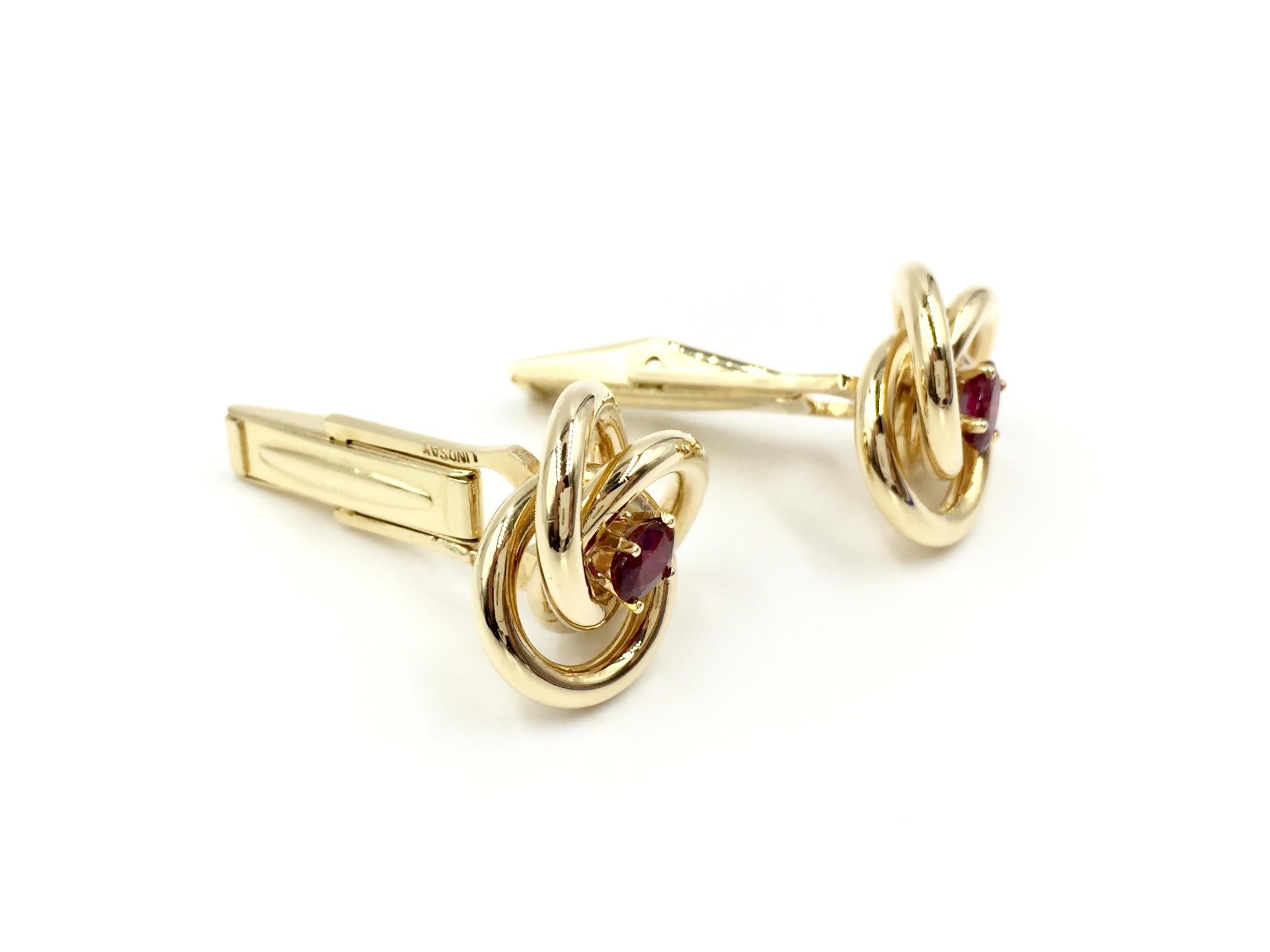 Timeless and stylish, these polished open knot cuff links feature oval rubies in the center. Made by Lindsay Co.
Ruby measures 5.5mm x 3mm, approximately .32 carats each. Knot measures 17mm across.
Each cuff link weighs 8.5 grams