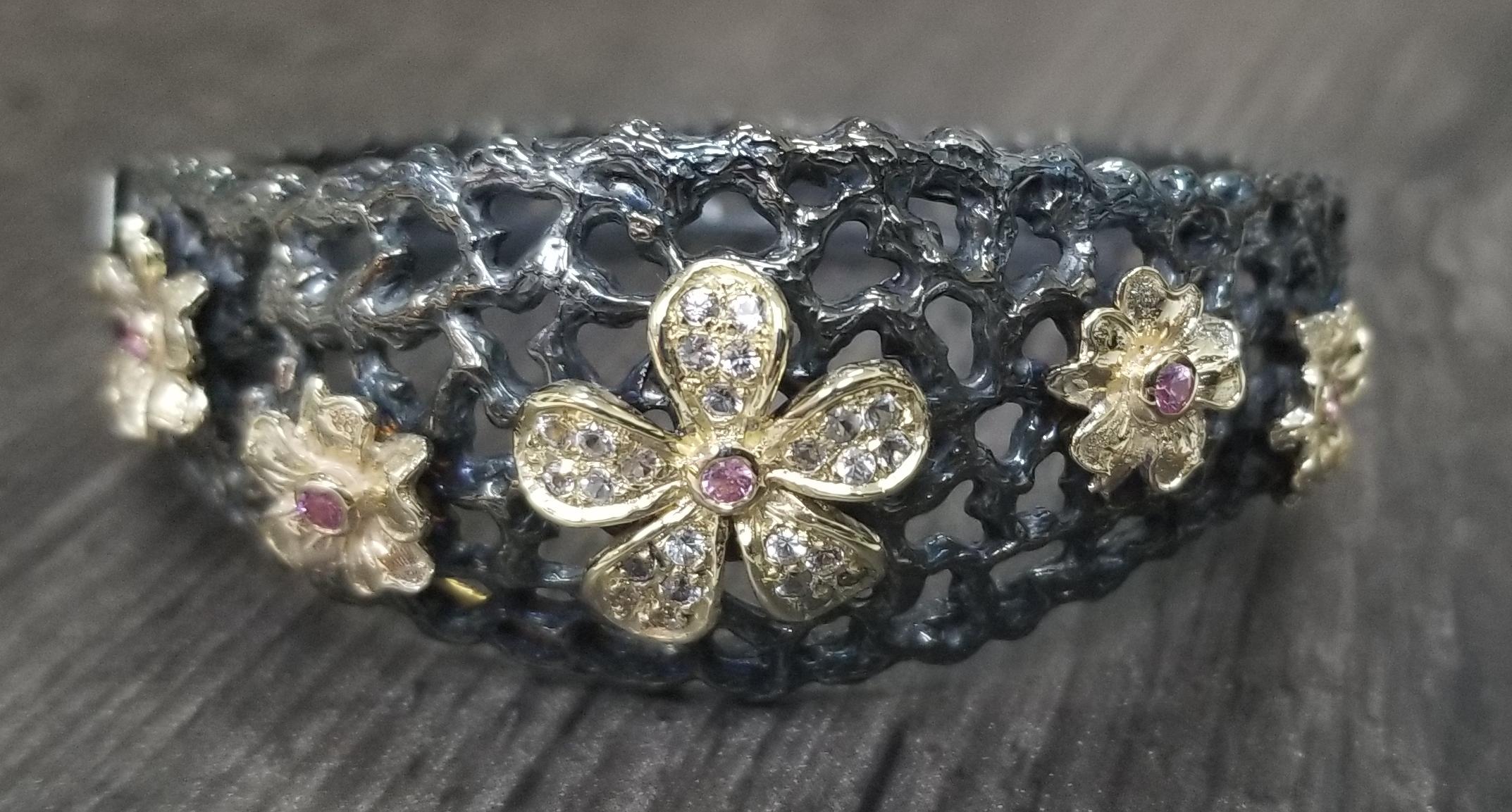 14k yellow gold flowers and Gresha signature bark bracelet in sterling silver antiqued.  The flowers are set with white and pink sapphires weighing .80pts.  The bracelet is hinged for tight fit, it can be modified to please.  
*this design is ours