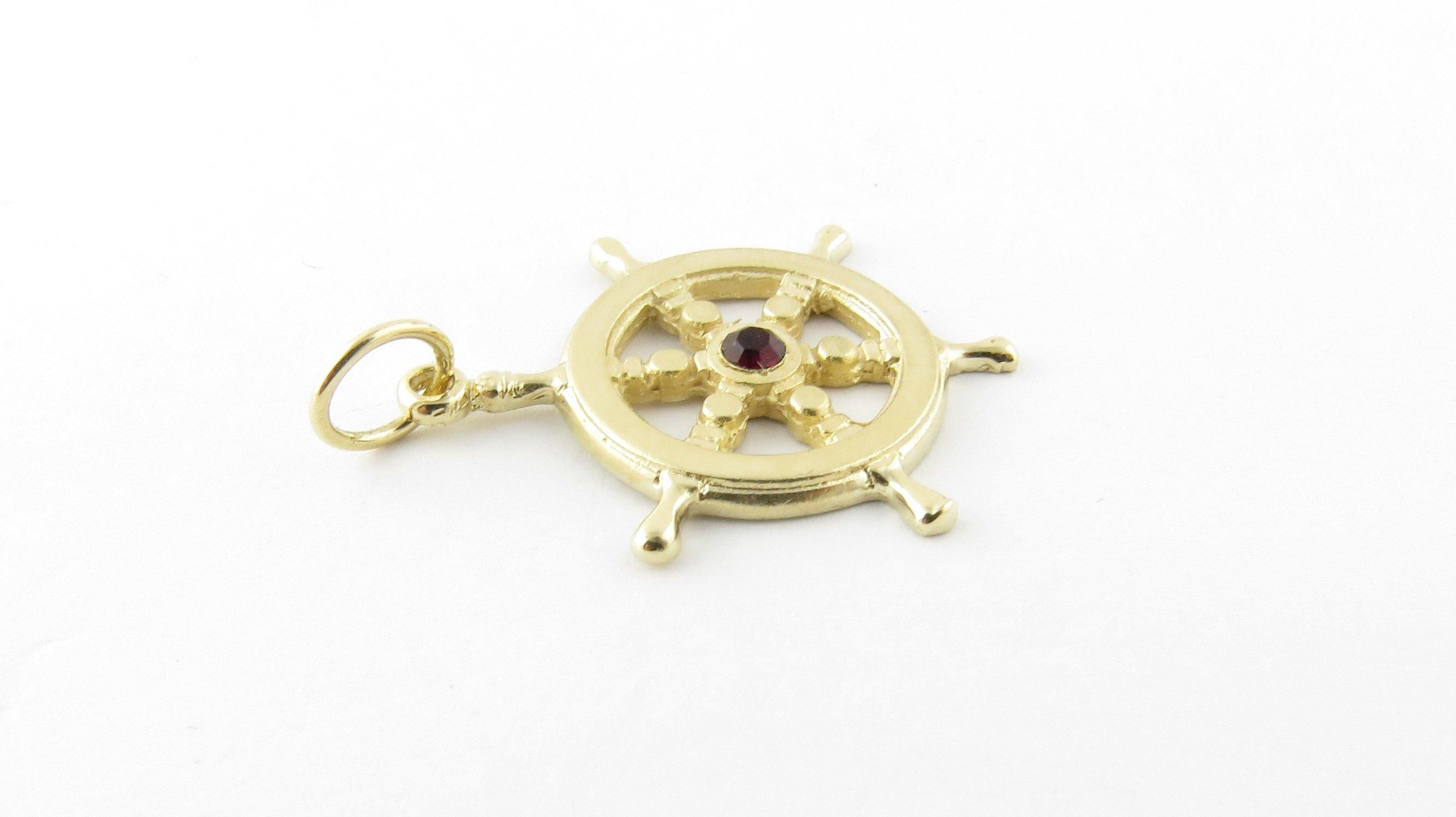 Vintage 14 Karat Yellow Gold and Synthetic Ruby Ship's Wheel Pendant. This nautical pendant features a miniature ship's wheel accented with a synthetic red ruby in its center.
Size: 27 mm x 23 mm Weight: 2.0 dwt. / 3.2 gr. Stamped: 14K Very good