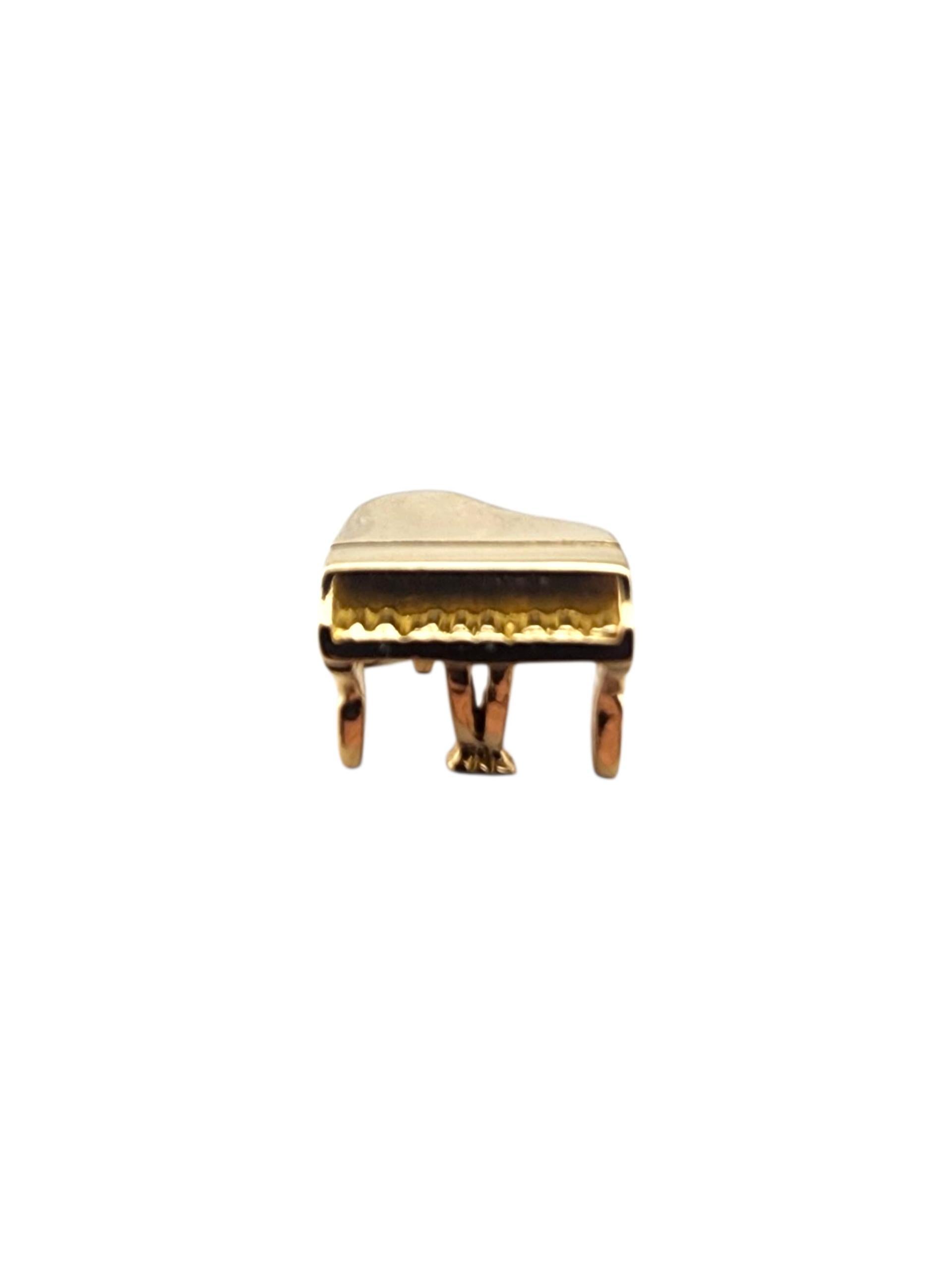 Charm a forma di pianoforte a coda articolato in oro giallo 14 carati.

Questo charm a forma di pianoforte articolato in oro giallo 14 carati è caratterizzato da un coperchio mobile che si apre e si chiude, un capolavoro giocoso in miniatura