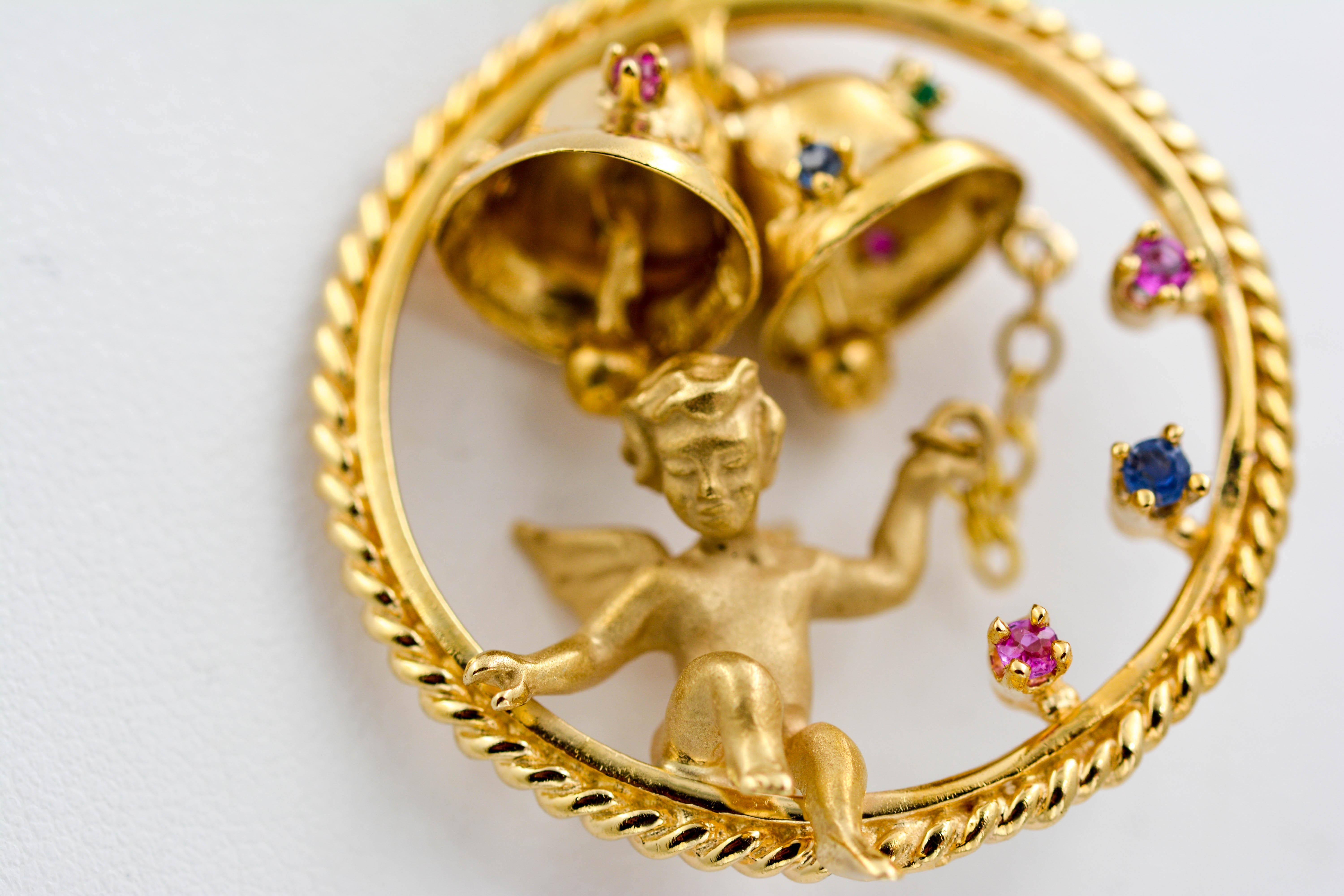 This detailed adorable charm is a custom made piece crafted in 14K Yellow Gold and accented with gemstones. The angel is happily ringing the bells above his head as he looks down beyond the heavens. The angel sits among four round rubies 