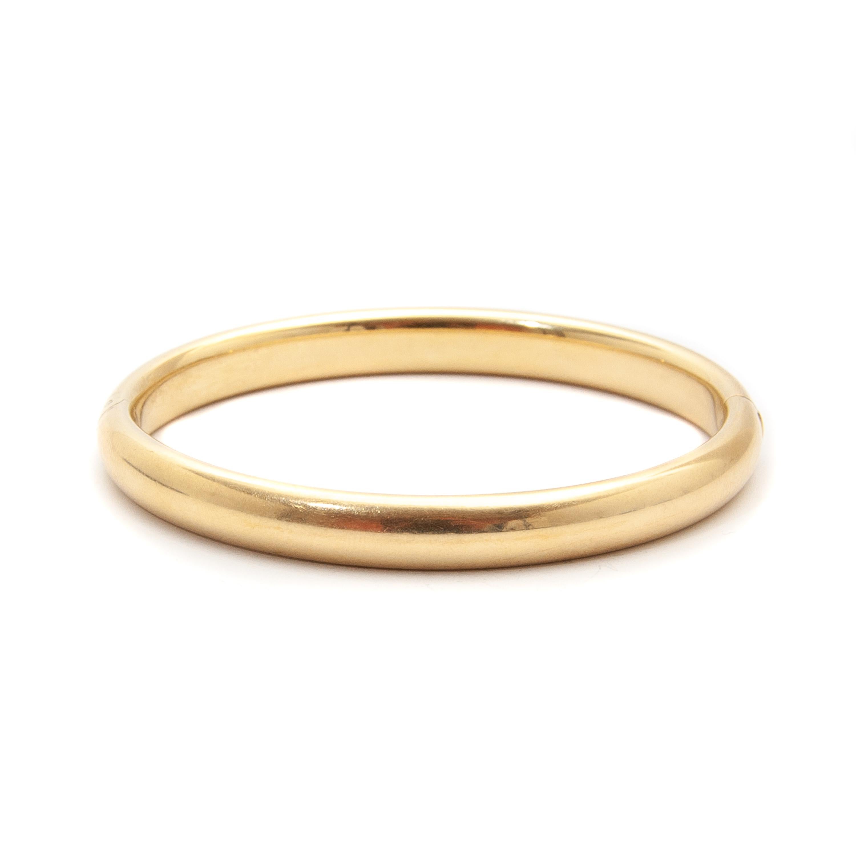 This timeless bangle bracelet is made of 14 karat yellow gold. It has a wonderful warm glow and an extra heavy weight of 21.9 grams. The bracelet has a nice height of 8 millimeters, is oval shaped and hinged. The bracelet is marked at its closure