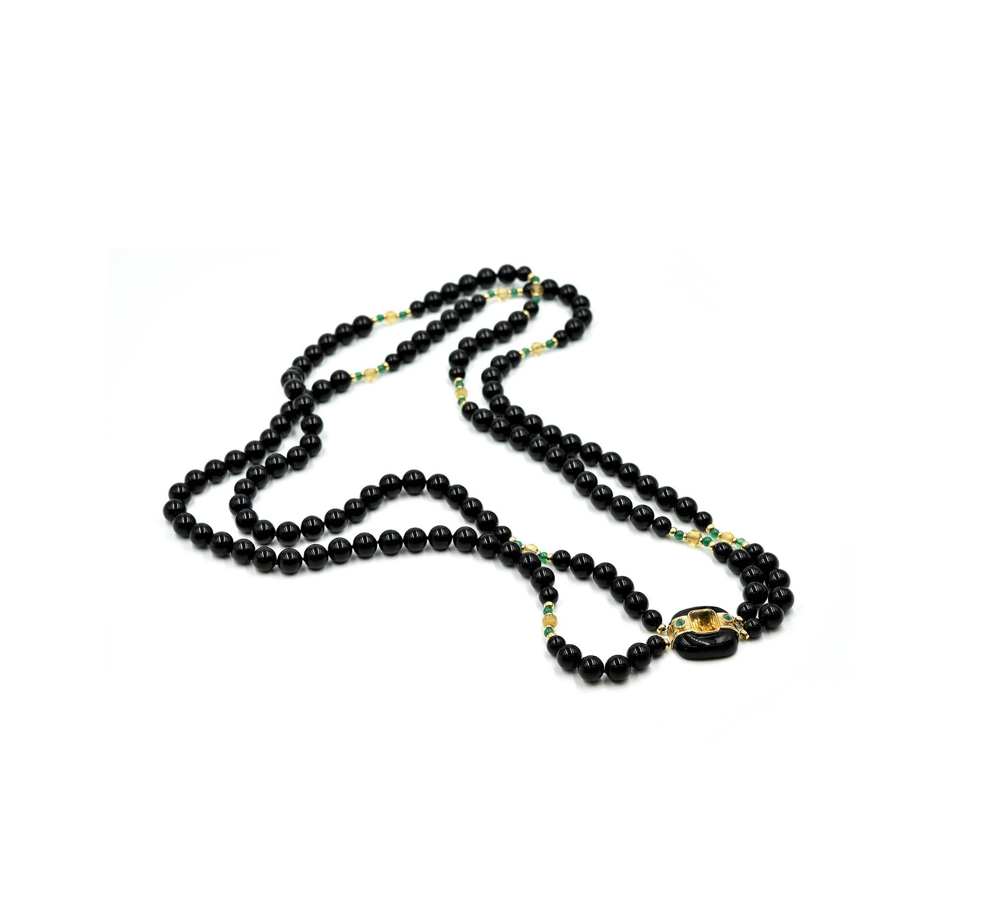 This is a 32” inch strand of beaded black onyx with a citrine and emerald pendant on the center. The strand has briolette cut cirtrine gemstones and cabochon round shaped emeralds stationed. The pendant features a cushion cut citrine gemstone that