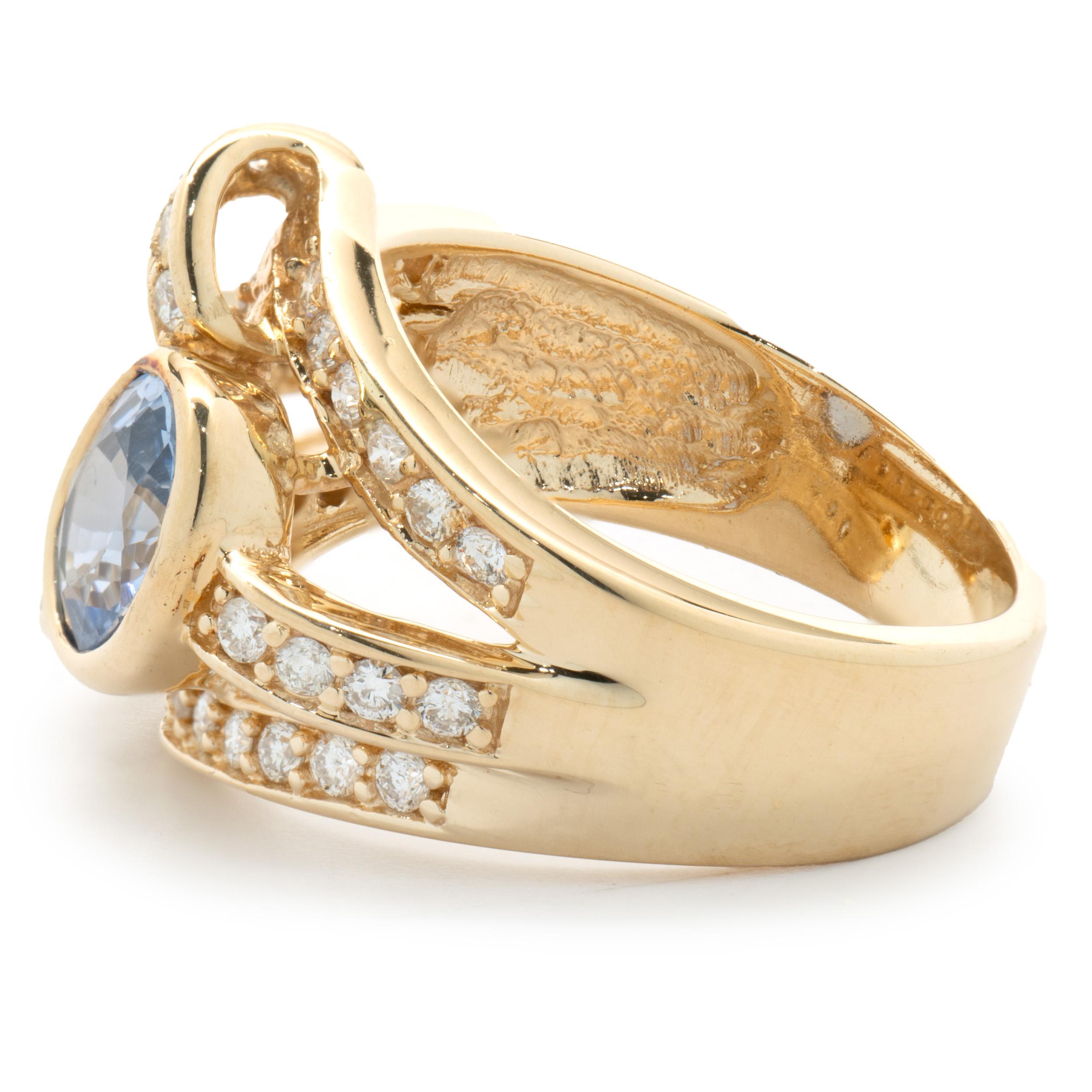 Oval Cut 14 Karat Yellow Gold Bezel Set Cornflower Blue Sapphire and Diamond Bypass Ring For Sale