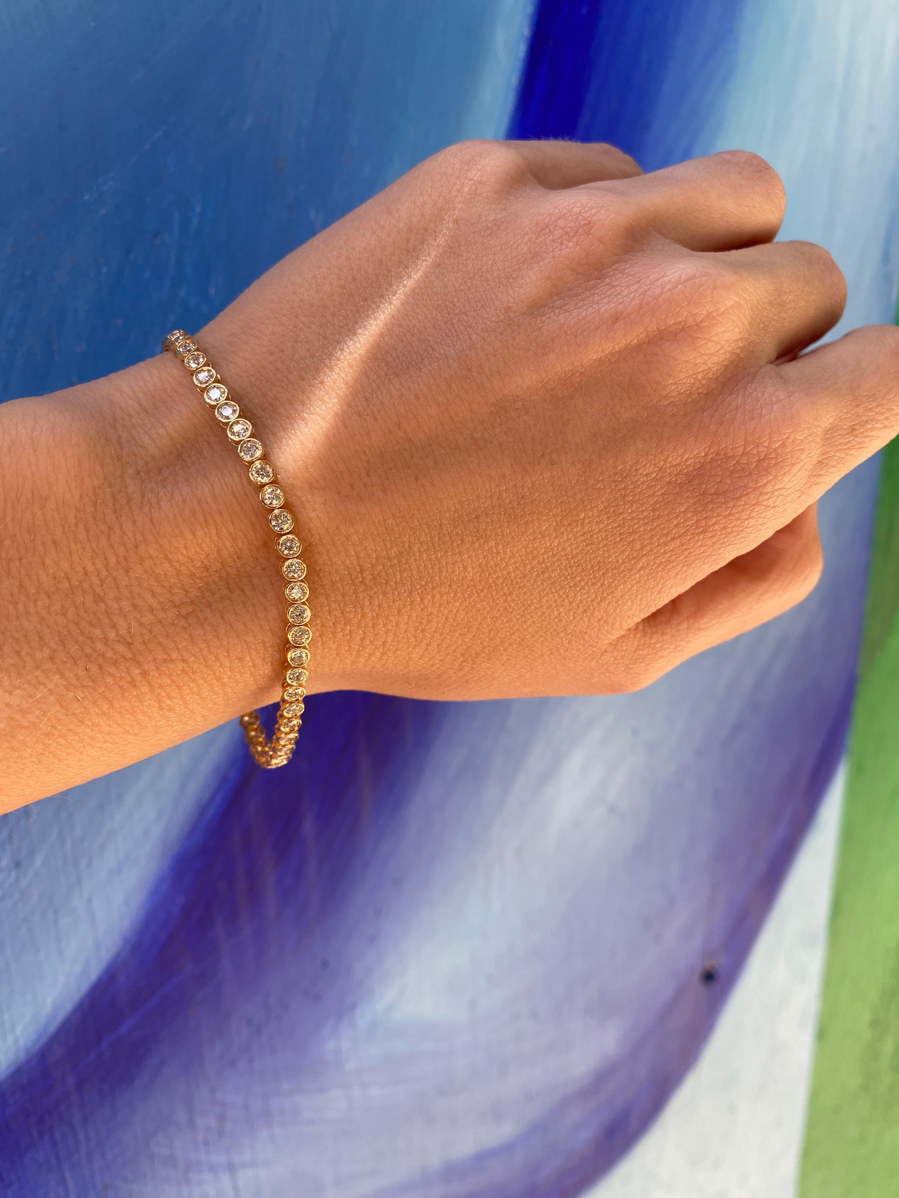 This elegant tennis bracelet showcases a breathtaking arrangement of 55 round diamonds with a total weight of 3.12 carats, meticulously bezel set in radiant 14 karat yellow gold. Perfect for both casual and formal occasions, this exquisite piece