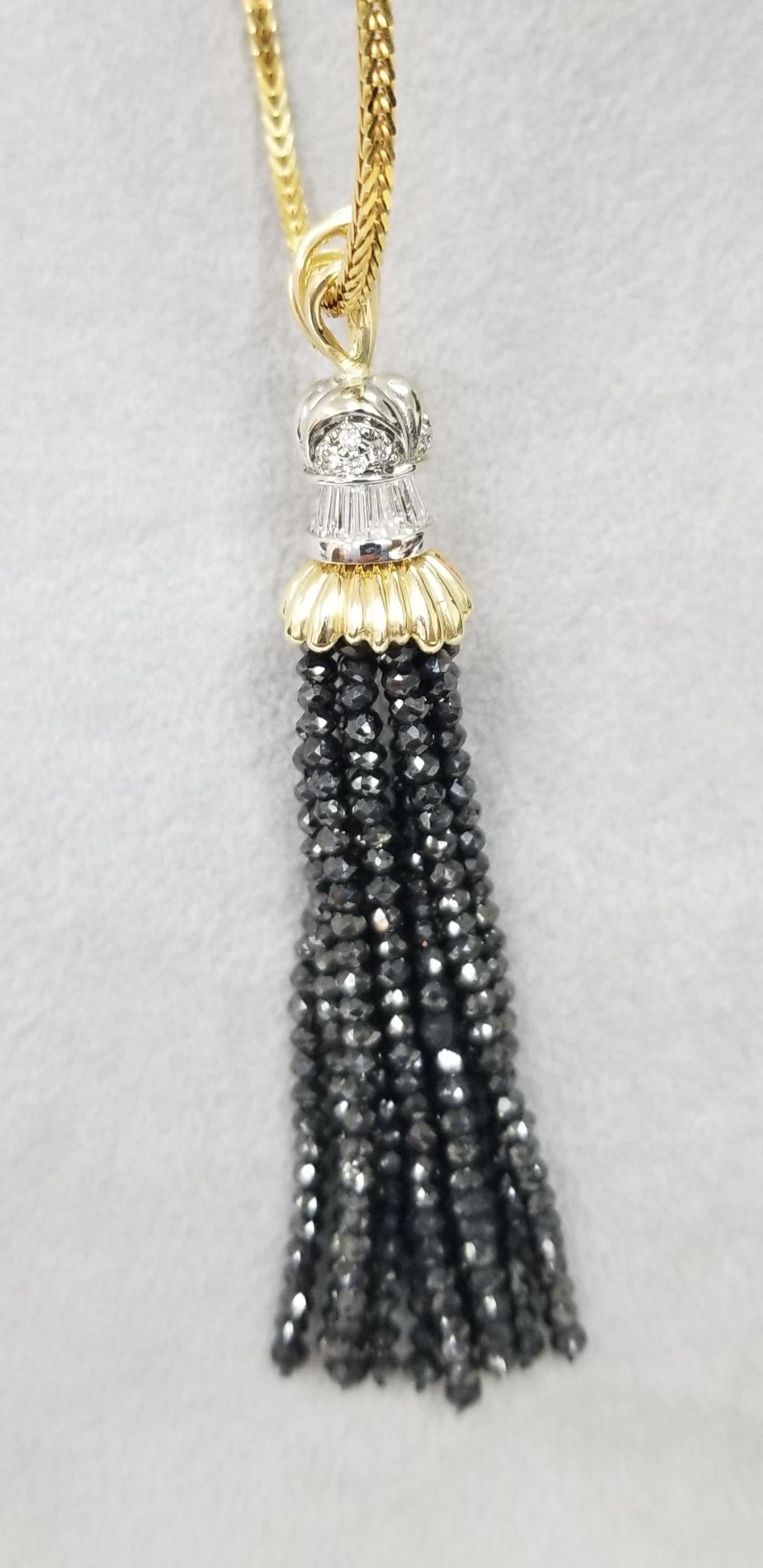 14k yellow gold diamond pendant containing 12 baguette cut diamonds weighing 1.10cts. and 15 round diamonds weighing .25pts. set in a 14k white gold setting with 10 strands of  black faceted diamond weighing 35.25xcts. hanging as tassels.  on a 24