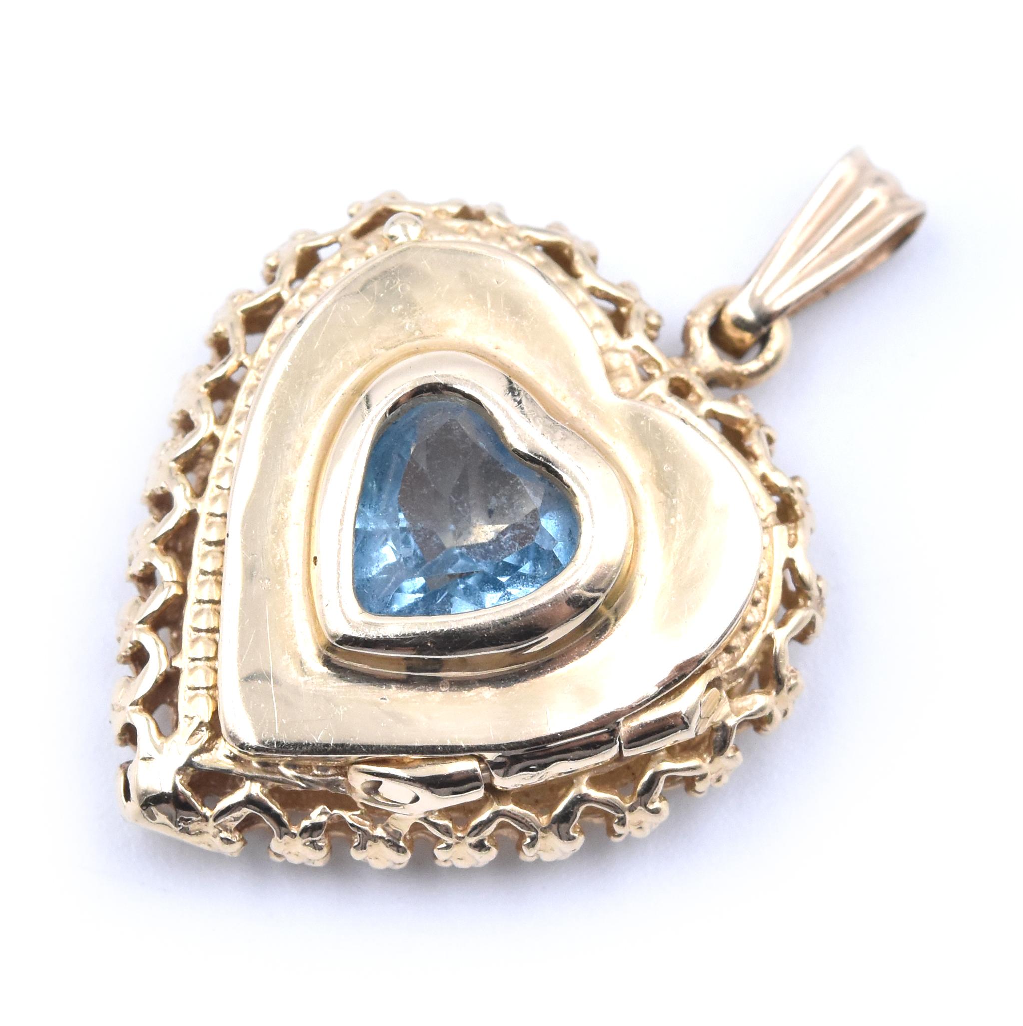 Designer: custom
Material: 14K yellow gold
Blue Topaz: 1 heart cut = .60ct
Dimensions: the pendant measures 28.5mm x 19.5mm 
Weight: 4.20 grams
