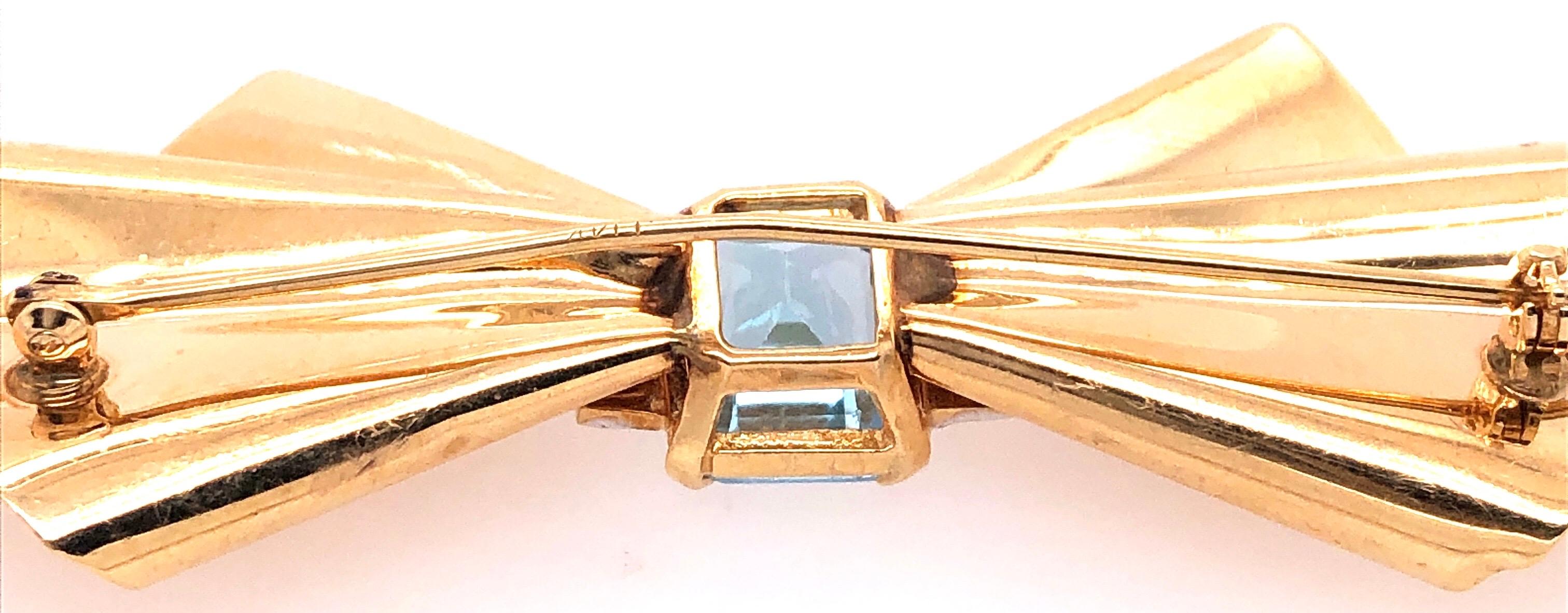 14 Karat Yellow gold Bow Brooch with Blue Topaz and Diamond Accents
0.12 total diamond weight
8.40 grams total weight.