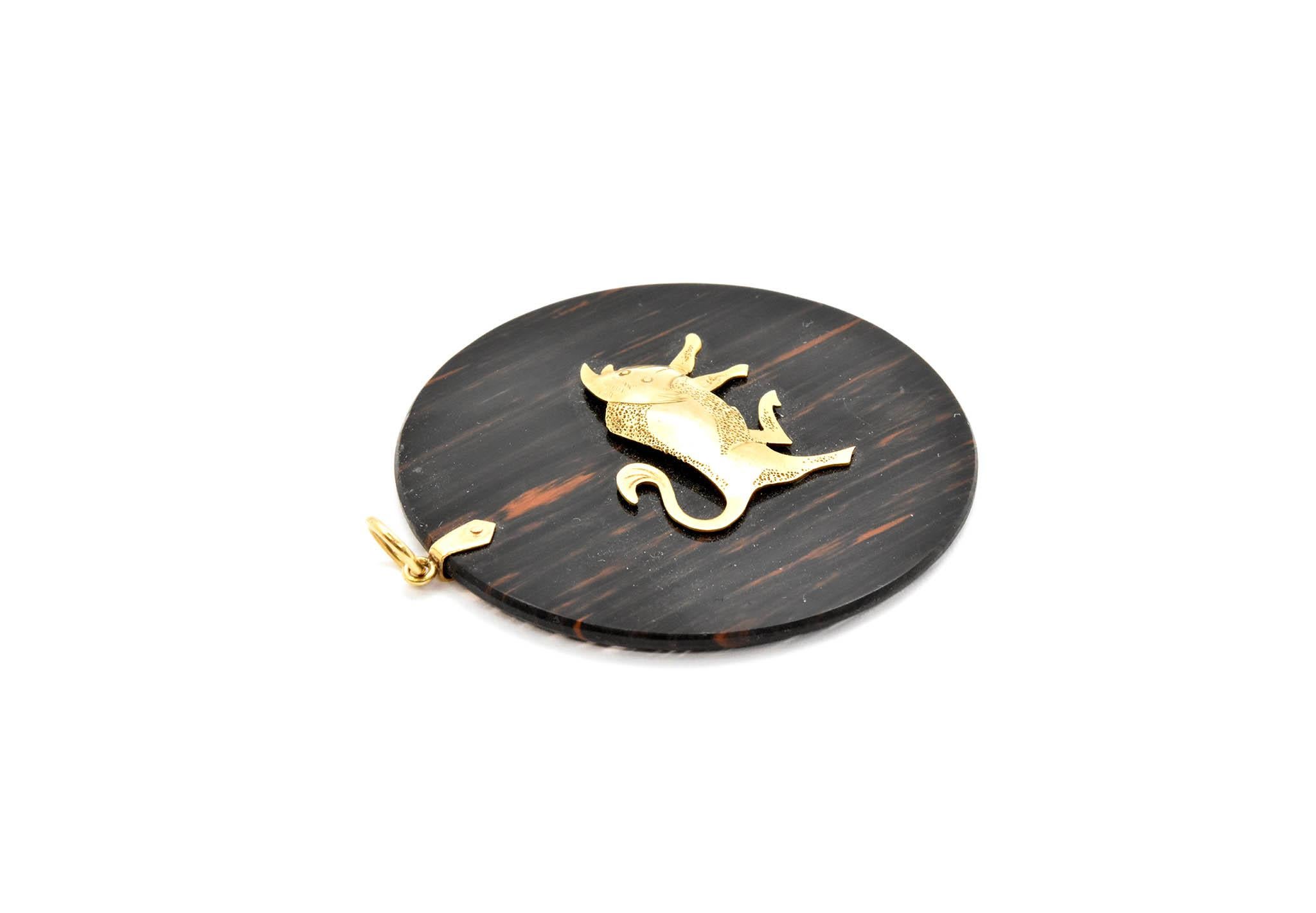 This large pendant features a 14k yellow gold bull on a circular piece of stone. The pendant measures 50mm in diameter, and it weighs 12.2 grams.

