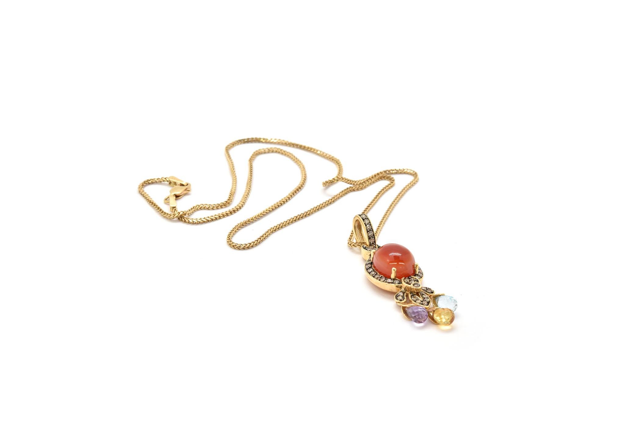 This necklace features a 14k yellow gold and carnelian pendant on a 14k yellow gold chain. The carnelian is surrounded by a bezel of diamonds for a total weight of 0.40ct. The pendant is finished with 3 colored quartz rondelles. The pendant measures