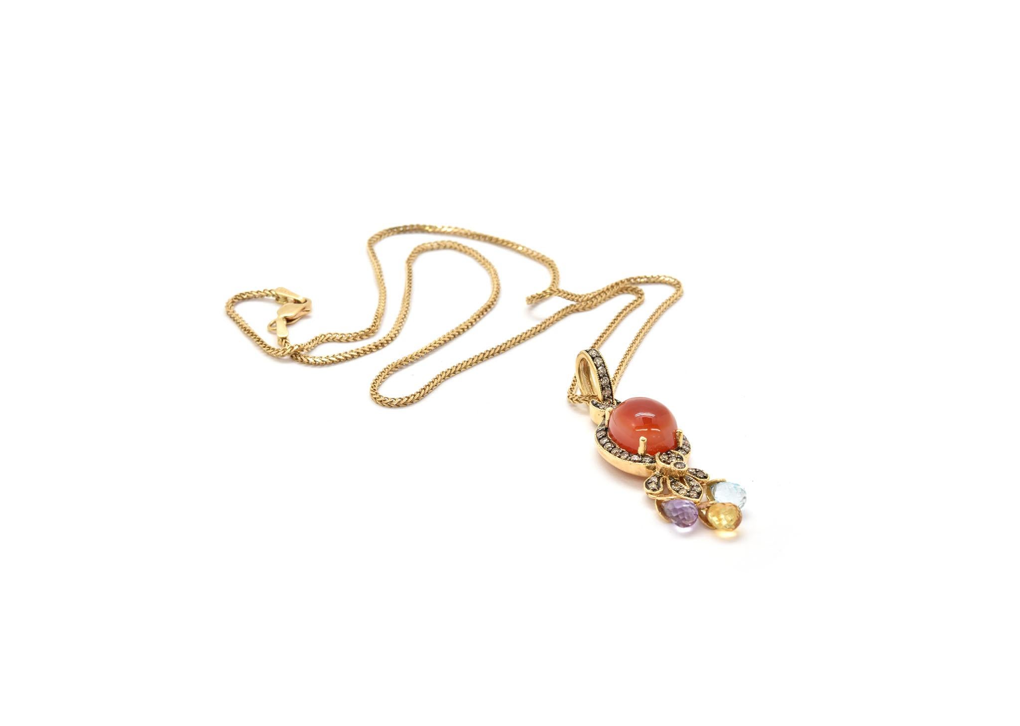 Ce collier présente un pendentif en or jaune 14k et cornaline sur une chaîne en or jaune 14k. La cornaline est entourée d'une lunette de diamants pour un poids total de 0,40ct. Le pendentif est terminé par 3 rondelles de quartz coloré. Le pendentif