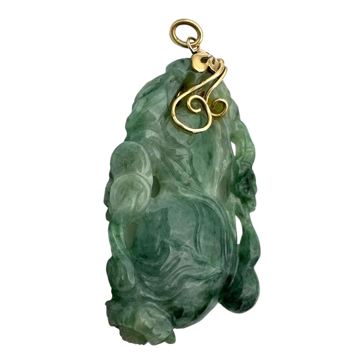 Ce pendentif en or jaune 14 carats est orné d'une vigne de lotus magnifiquement sculptée et d'une superbe pierre de jadéite verte. D'une longueur de 2 pouces, il constitue un magnifique ajout à tout collier ou chaîne. Les détails complexes et les