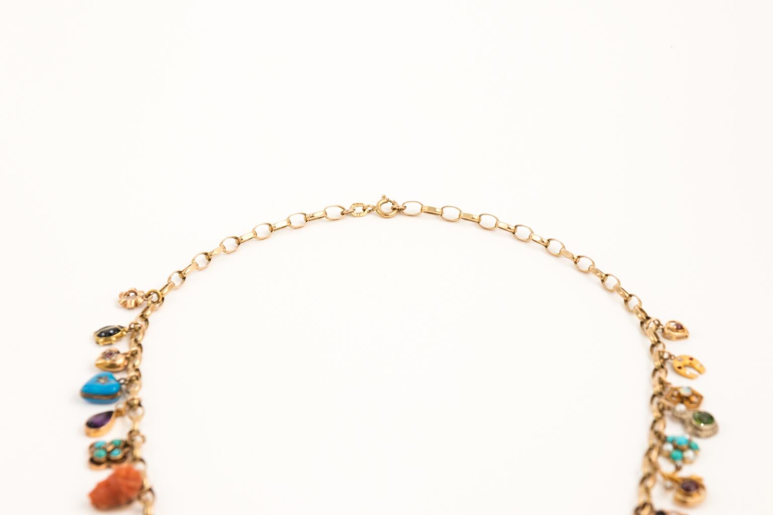 Antique 14 Karat Yellow Gold necklace with twenty seven charms made from: Diamond,Seed Pearl,Amethyst, Peridot,Coral,Garnet,Agat,Topaz,Turqoise, and Enamel.
