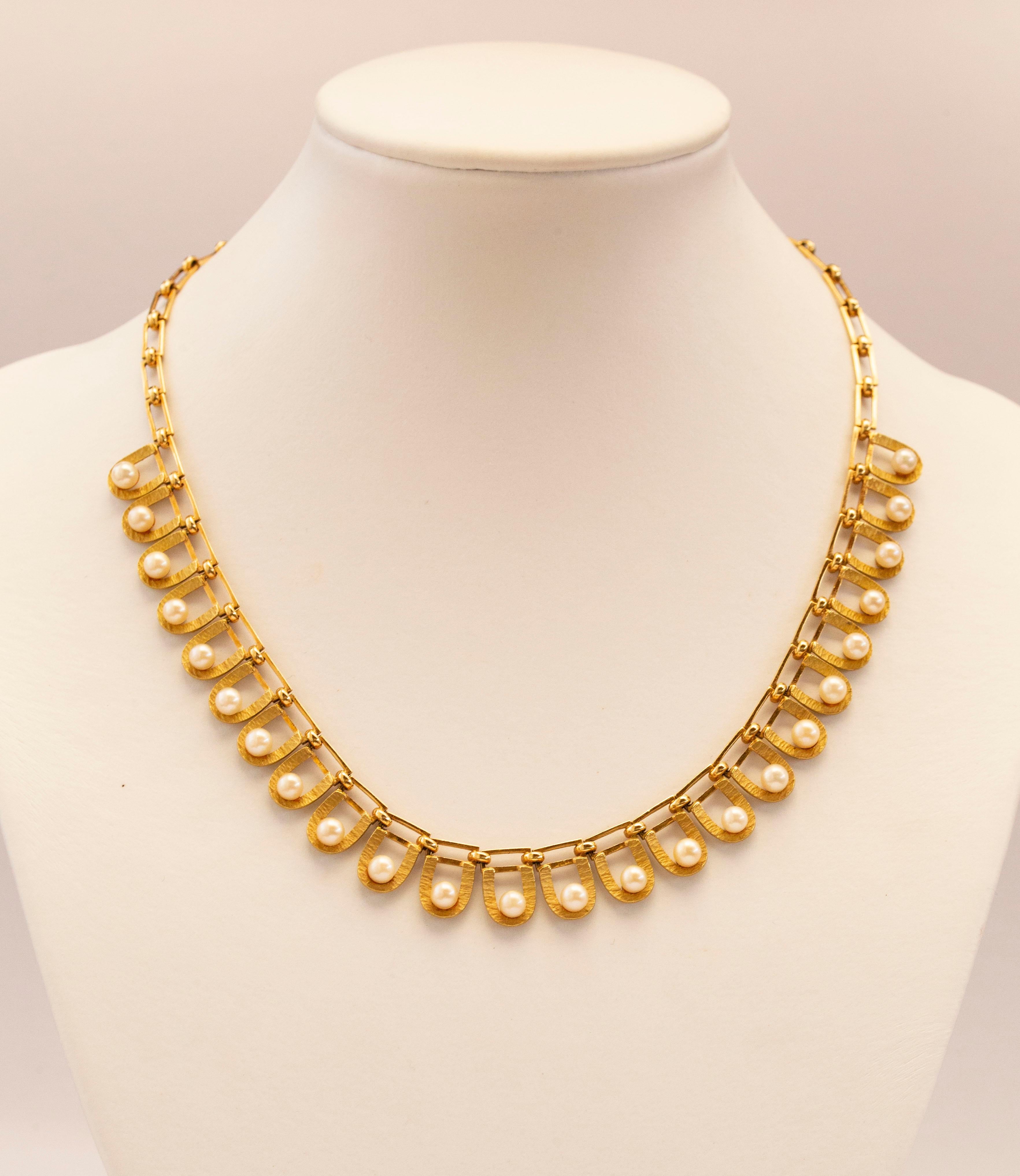 A vintage 14 karat yellow gold necklace with twenty-four cultivated Akoya pearls set individually in yellow gold matt and textured links in a form of a horseshoe that are attached to rectangular links made of yellow shiny gold. The necklace has a